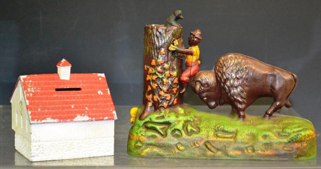 Two Metal Banks: Two banks, including a PA Dutch Bank Barn with Hex Sign bank made of cast aluminum, as well as an after market bank from The Book of Knowledge featuring a man a tree and an American Bison