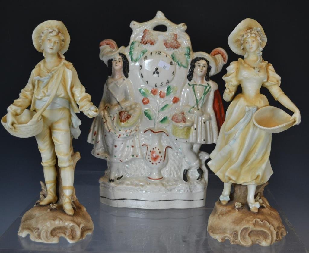 Staffordshire Figure & German Porcelain: Staffordshire figure of man and woman standing by a clock, 12.5"h; along with 2 German porcelain figurines