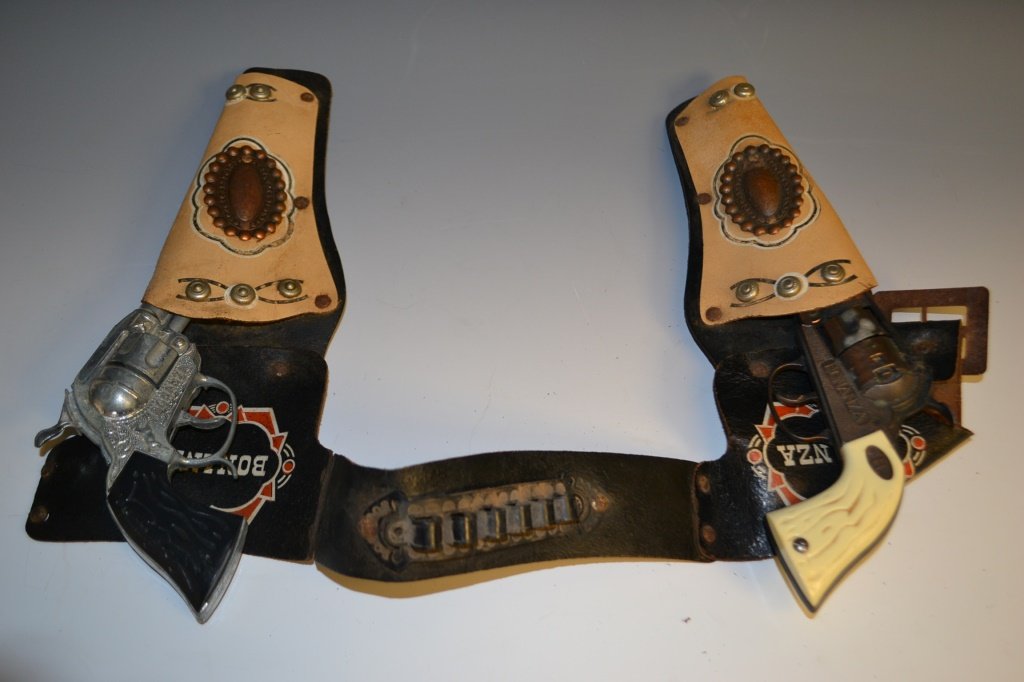 Bonanza Leather Gunbelt, Pistols, and badges: Bonanza leather gunbelt and two pistols, as well as four badges; three featuring Hoss, Ben, and Little Joe and another earlier Bonanza badge that reads Bonanza Deputy Marshall with a red stone in the 