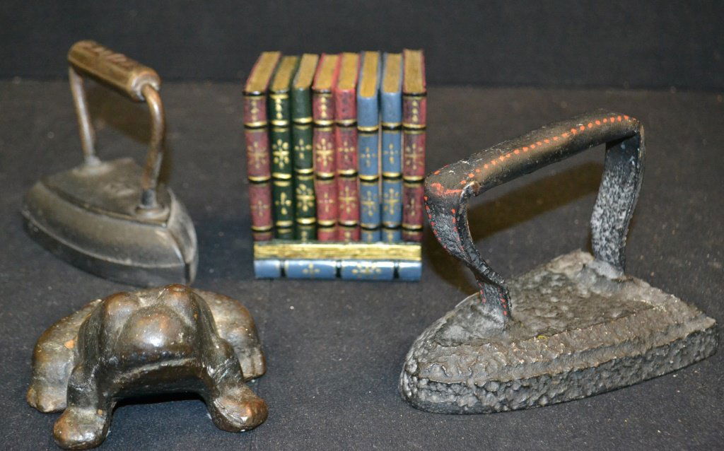 Cast Iron Door Stops & Book End: Three Cast Iron door stops & bookend, including; 2 sad irons commonly used as door stops, a cast iron frog door stop, and a book end that looks like books. frog measures 3"h x 4"w x 5"d