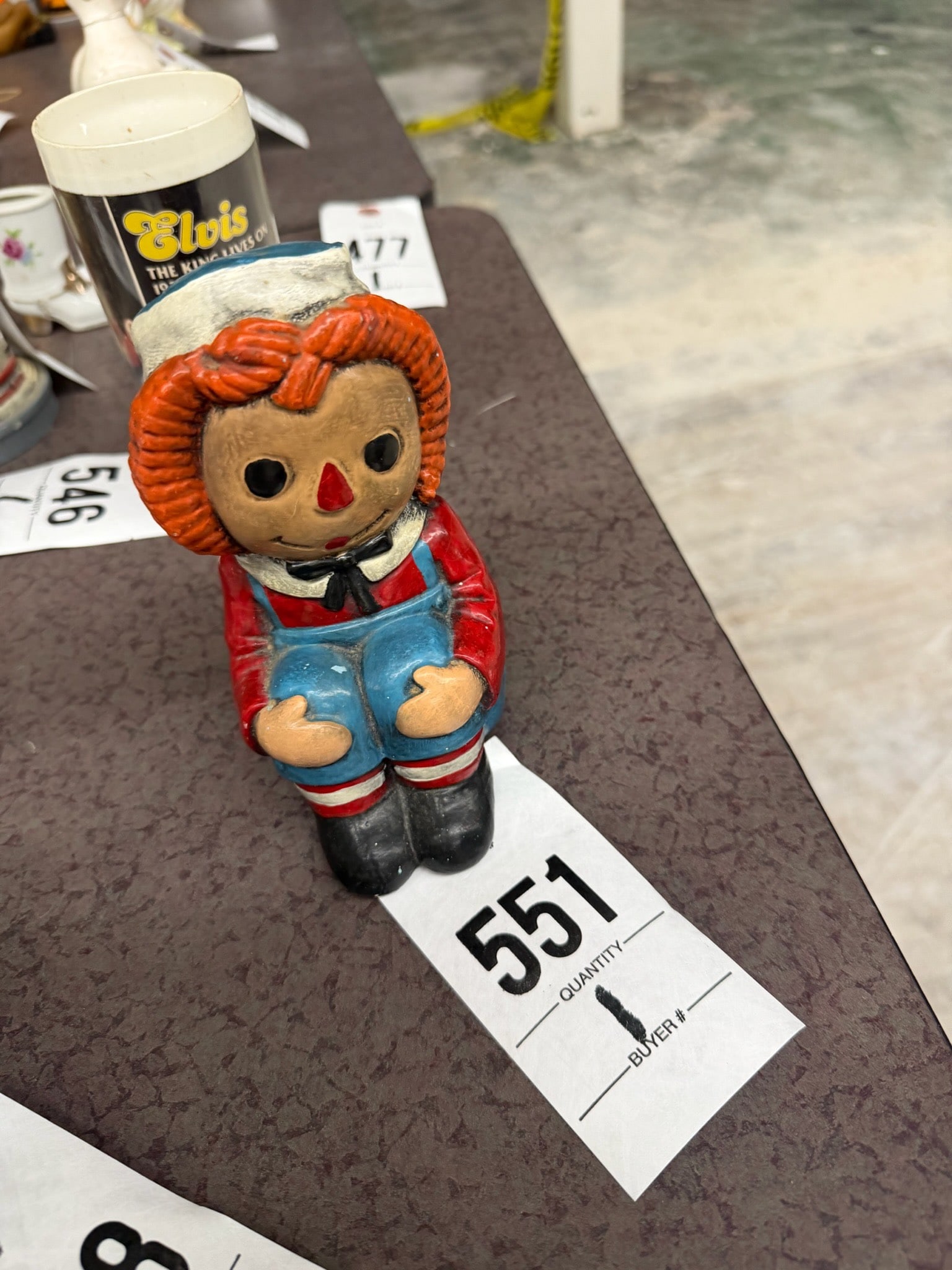 Raggedy Ann Figurine: Raggedy Ann ceramic figurine featuring red yarn hair and classic blue outfit, designed as a decorative piece.