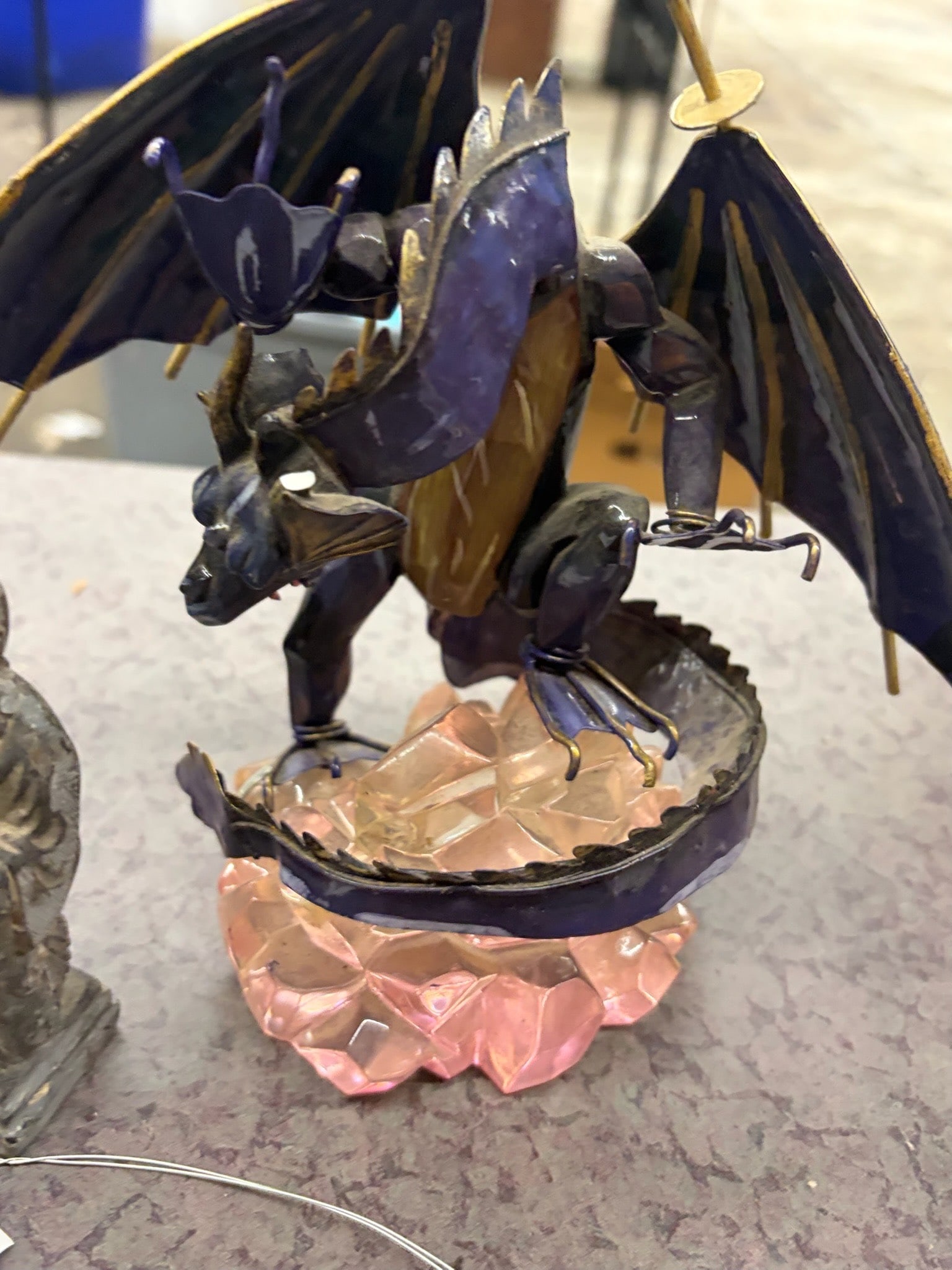 Figurines Lot, Including Dragon, Skull, and Statue: Figurines including a metal dragon on a pink crystal base, a small carved stone statue, a pirate-themed skull with eyepatch and decorative detailing, and a red dragon on a sculpted base. Materials inc