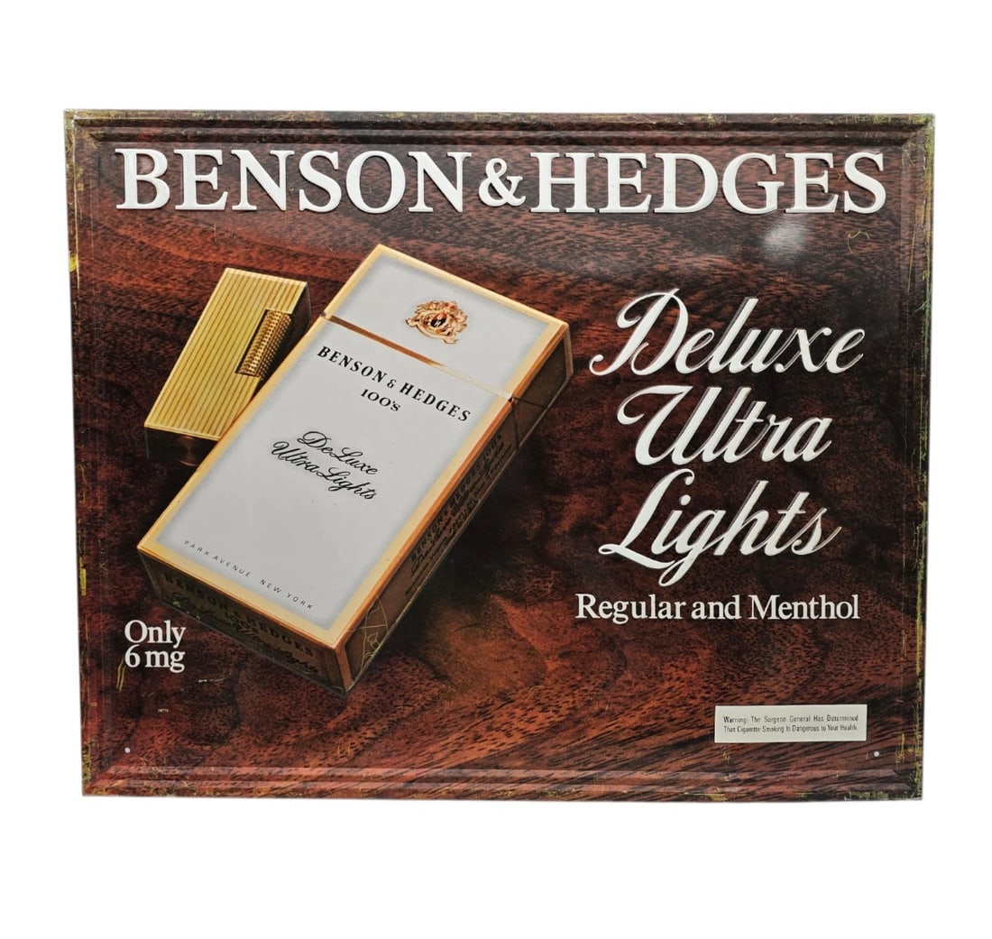 Vintage Benson & Hedges Deluxe Ultra Lights Metal Sign - Embossed Tobacciana Tin Sign: This highly detailed piece features a rich, warm faux-woodgrain background that gives it a sophisticated, library or lounge aesthetic.The top features the BENSON & HEDGES brand name in bold, stark whi