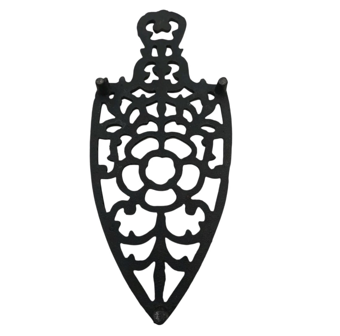 Cast Iron Trivet Black Floral & Leaf Design Vintage Iron Shape: detailed shield-shaped sad iron trivet boasting an elaborate openwork floral rosette at its center, surrounded by geometric lace or cathedral-style cutouts. This piece features a stylized handle loop 
