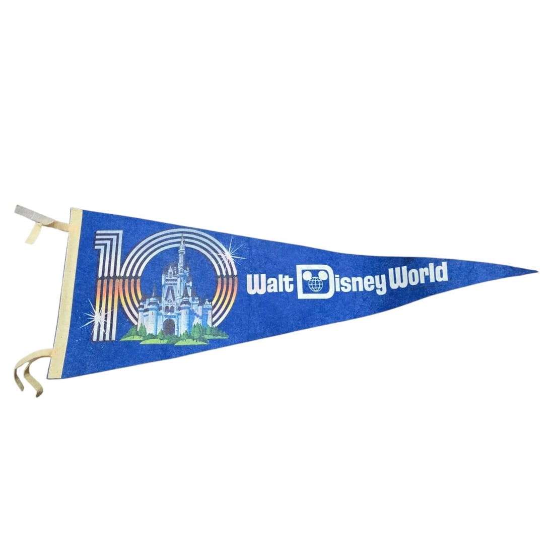 Vintage 1981 Walt Disney World 10th Anniversary Blue Castle Pennant: A vintage commemorative felt souvenir pennant celebrating the 10th Anniversary of Walt Disney World (1981). Features a rich royal blue felt body with the iconic retro "Walt Disney World" logo typograp