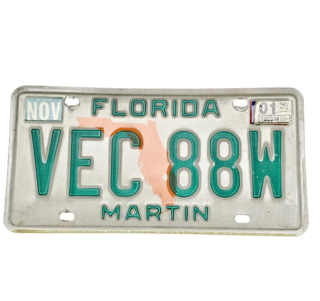 Florida License Plate VEC88W Martin County: A vintage metal Florida license plate featuring a prominent graphic silhouette of the state of Florida in orange right in the center. The plate features a debossed forest green alphanumeric text strin