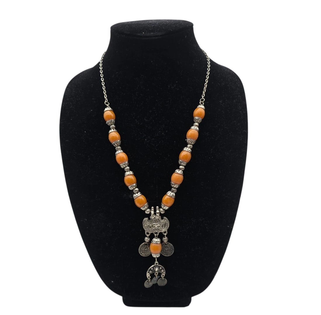 Vintage Boho Orange Resin Silver Tone Tribal Taviz Coin Amulet Pendant Necklace: tribal-style statement necklace featuring a fine silver-toned chain adorned with large, smooth, round amber-orange resin or stone beads. The center features an intricate, openwork silver pendant with 