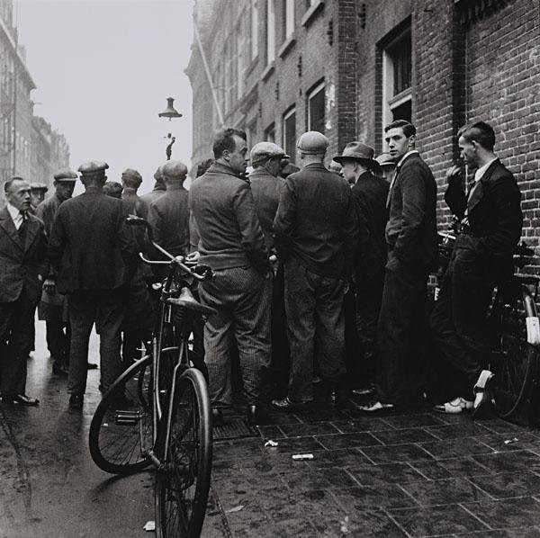 BESNYÖ, Eva (1910-2003).: BESNYÖ, Eva (1910-2003). Unemployed men in front of a social security office. Silver print, with the photographer's copyright stamp on the reverse 'Eva Besnyö Fotografe gkf Vondelstraat 92 Amsterdam