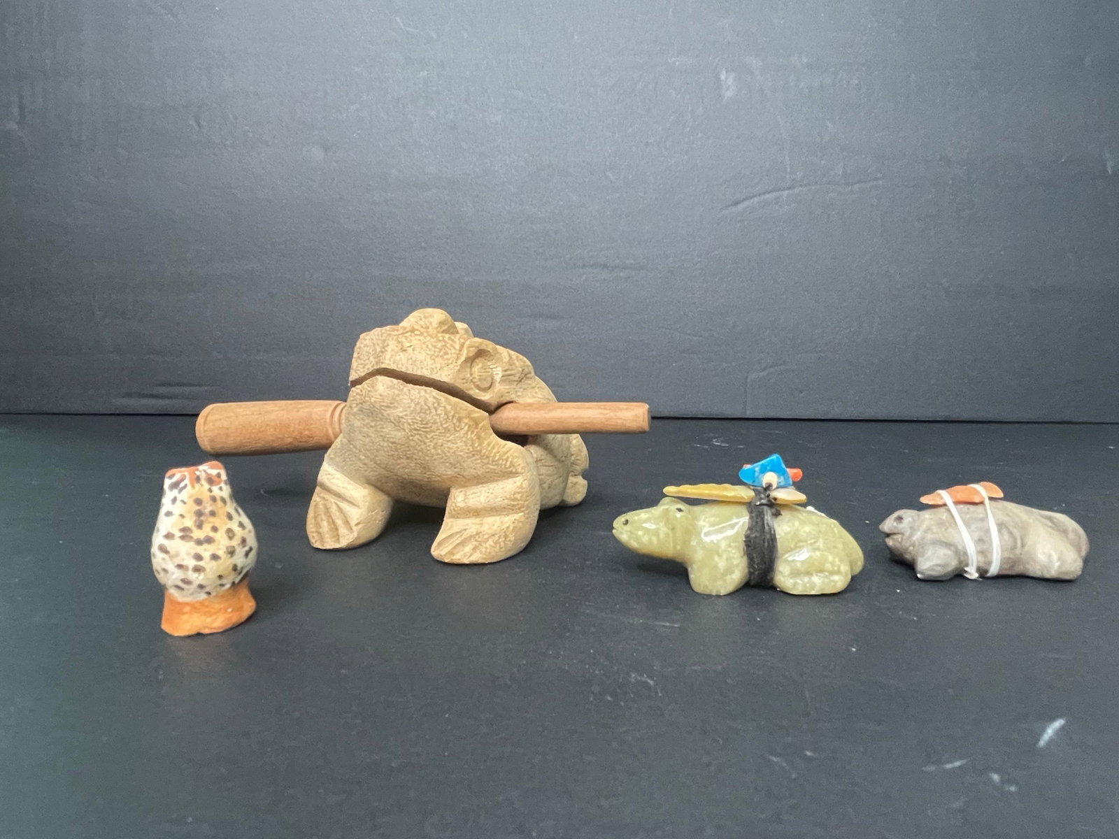 Wooden Frog Guiro Percussion Instrument and Stone Animal Figurines: This collection includes a wooden frog that functions as a guiro percussion instrument, with carved lines for texture and a dowel for scraping. It is accompanied by three small stone animal