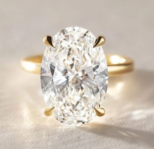 10 Carat Lab Grown Oval Hidden Halo Engagement Ring In 14kt Yellow Gold: 10 carat lab grown oval diamond set in a refined four-prong design. A hidden halo beneath the centre stone adds a soft glow, keeping the look clean and elegant from the top. Ring Us 7.00 us Ring Size 