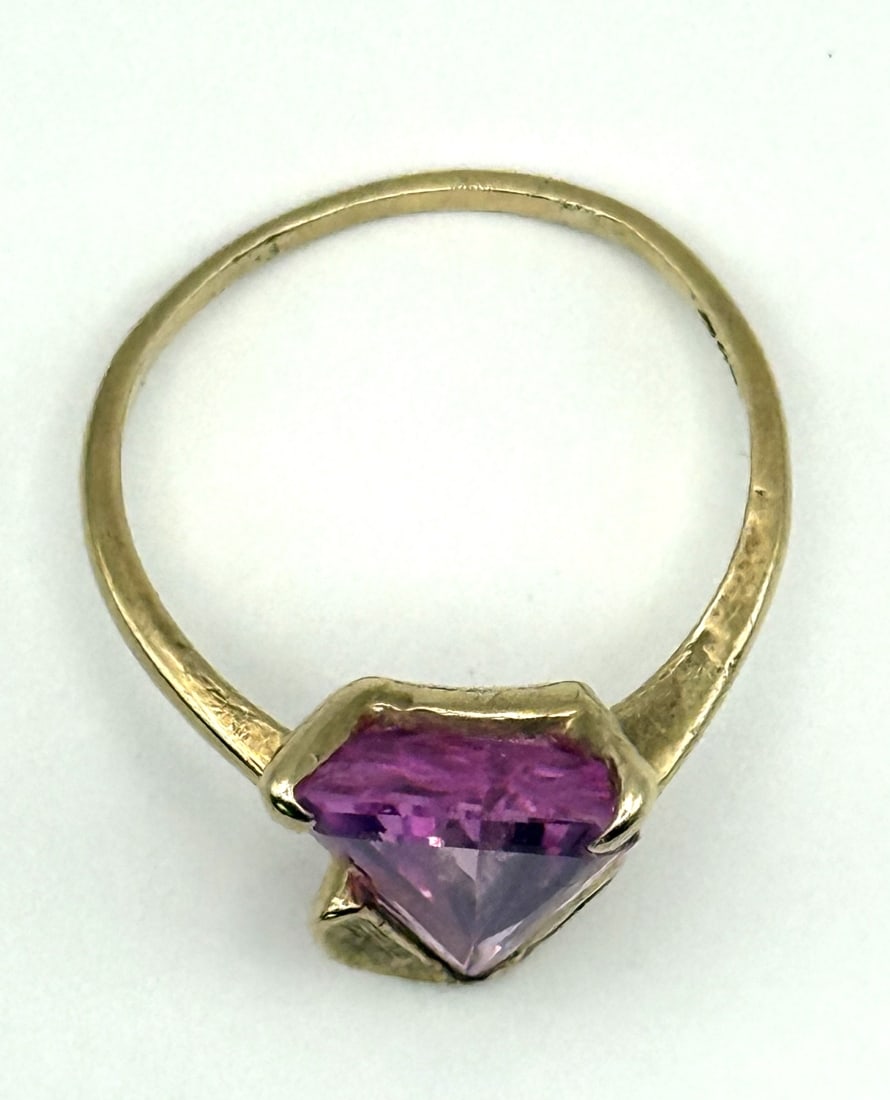 10K Yellow Gold Ring with Triangle Step Cut Synthetic Pink Sapphine: 10K yellow gold ring set with a triangle step?cut synthetic pink sapphire measuring approximately 14.16 mm x 9.97 mm x 5.0 mm, with an estimated weight of 4.6 carats. Total ring weight: 3.62 grams.
