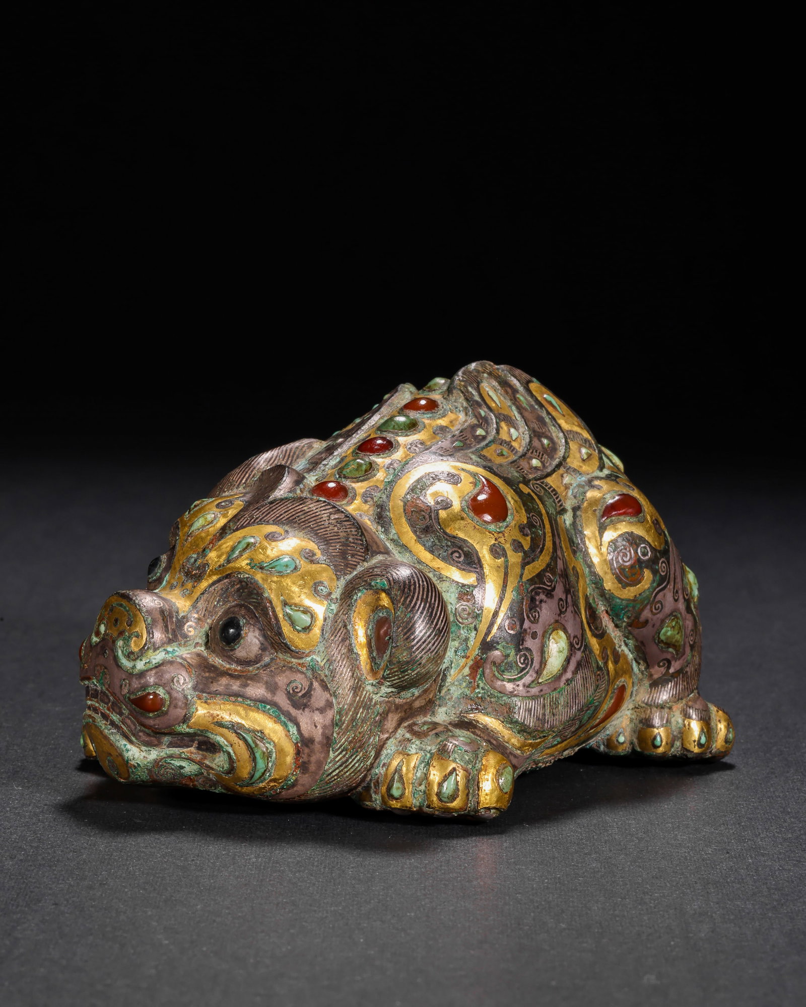 HAN DYNASTY COPPER INLAID GOLD AND SILVER INLAID GEMSTONE AUSPICIOUS BEAST TOWN: H:4cm(1.57in) W:10cm(3.94in) Weight:460g(1.01lb)This artifact is cast in bronze, fully decorated with patterns on the beast's body using gold and silver inlay technique, inlaid with red and green gems