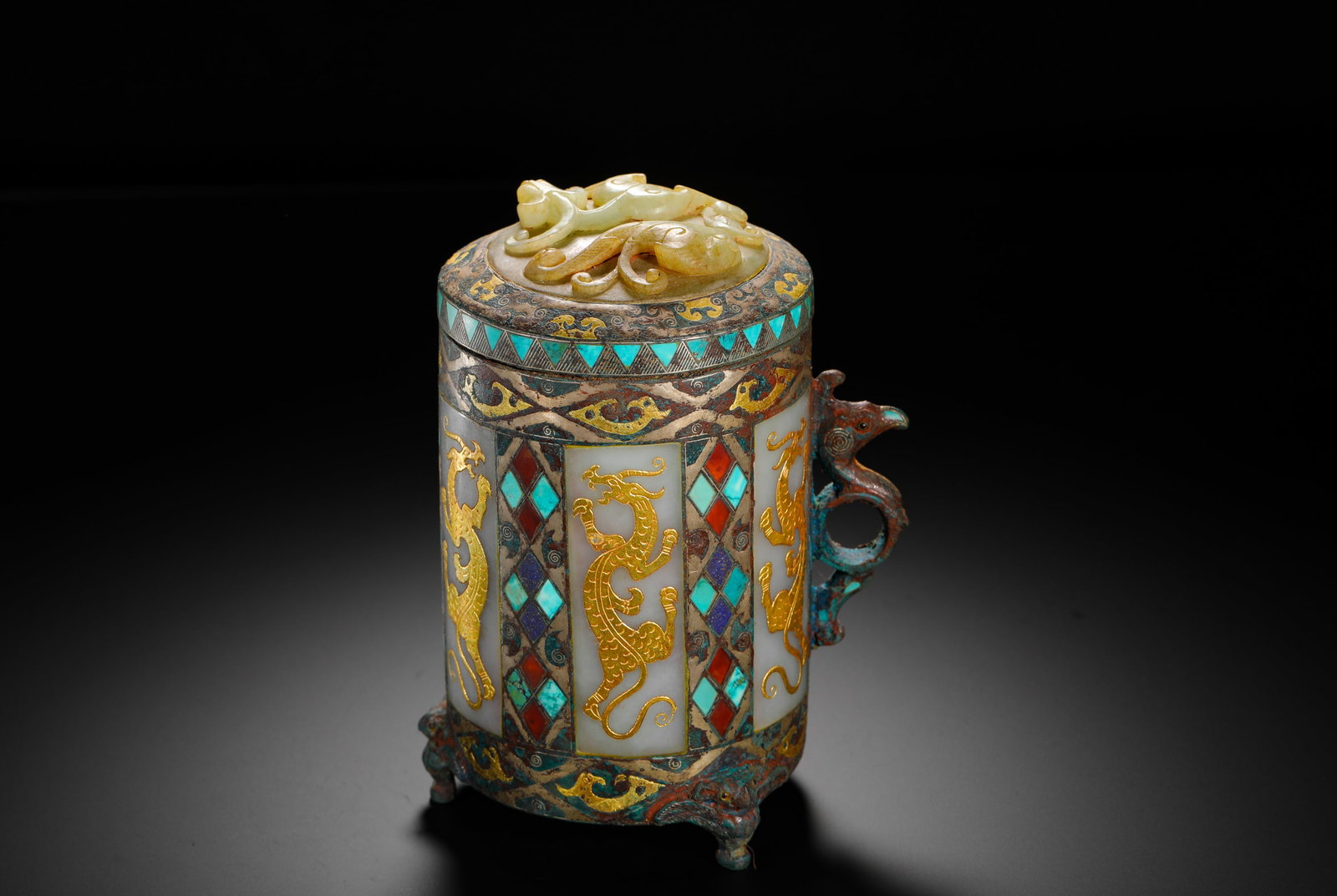HAN DYNASTY INLAID GOLD AND SILVER INLAID JADE INLAID GEMSTONE DRAGON AND PHOENIX EAR BRONZE : H:15cm (5.91in) W:12.5cm (4.92in) Weight:1140g (2.51lb)A Han Dynasty bronze wine zhi cup with phoenix handle, inlaid with gold, silver, white jade and gemstones. Straight cylindrical body with a phoen