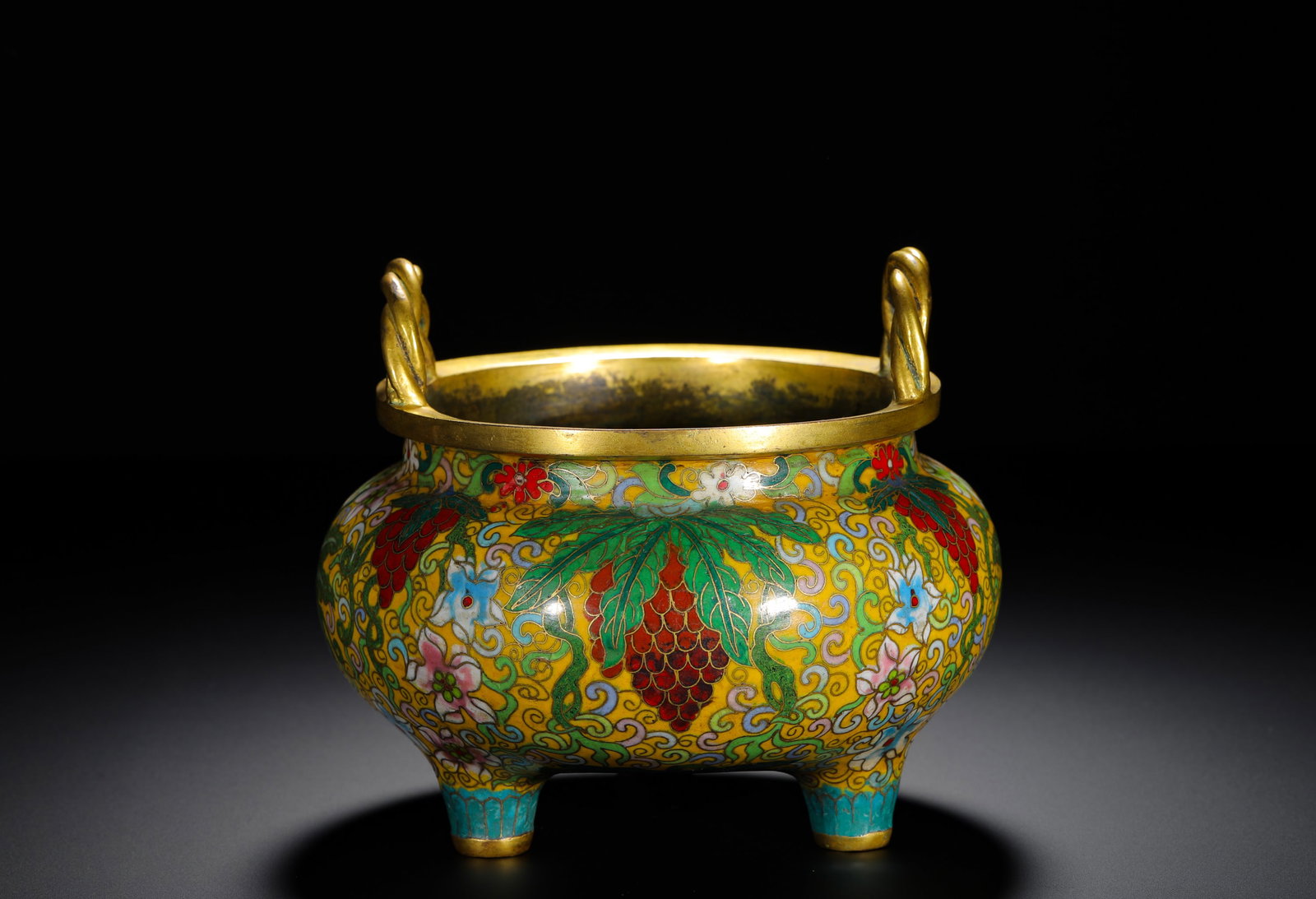 BRONZE BODY CLOISONNE ENAMEL YELLOW GROUND GRAPE-PATTERNED ROPE EAR TRIPOD STOVE OF THE QING DYNASTY: H:13cm (5.12in) D:15cm (5.91in) Weight:1700g (3.75lb)Gilt twisted-rope handles tripod censer, yellow cloisonne ground entwined grape vines, studio mark on base.