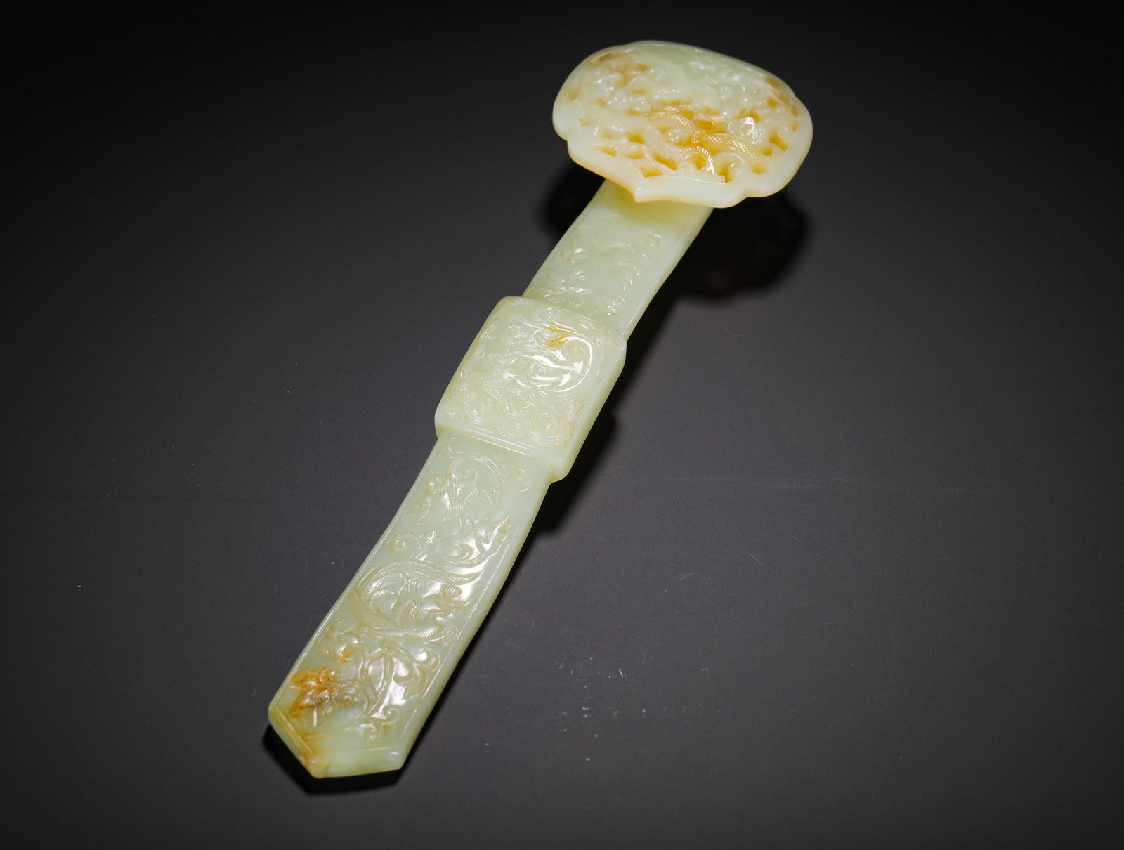 QING DYNASTY HETIAN JADE DRAGON AND PHOENIX PATTERNED RUYI: H:29.5cm (11.61in) W:8cm (3.15in) Weight:440g (0.97lb)This is a Qing Dynasty Hetian jade ruyi scepter, carved from smooth bluish-white jade with natural patina, with some parts presenting a yellowish-