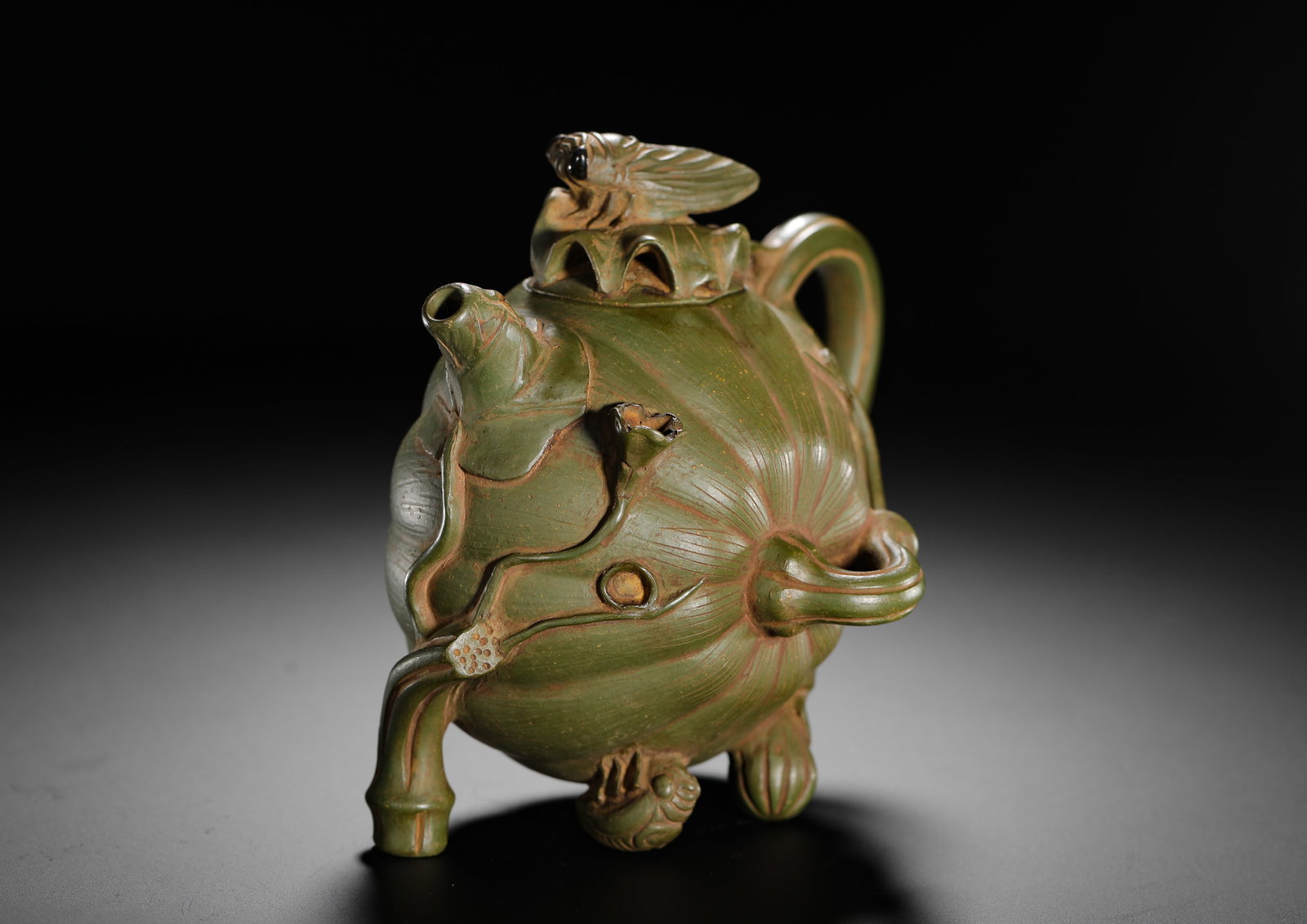 GREEN CLAY LOTUS POND CICADA PURPLE CLAY TEAPOT OF THE REPUBLIC OF CHINA ERA: H:14cmW:14cmWeight:430g Biomorphic floral Zisha teapot crafted from rare Republic-period green clay, modelled as lotus seedpod with full carved petal ribs. Spout shaped as lotus stem with seed pod, cu