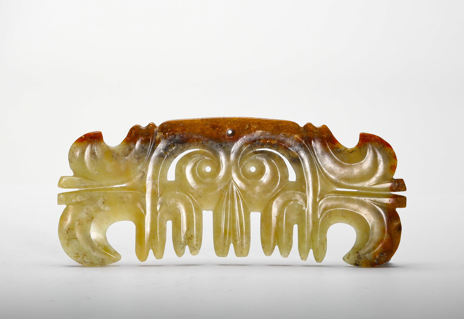A JADE PENDANT IN THE SHAPE OF A CLOUD FROM THE HONGSHAN CULTURE: H:21cm (8.27in) W:8.5cm (3.35in) Weight:230g (0.51lb)This is a hook-shaped cloud pattern jade pendant from the Hongshan Culture, carved from serpentine jade. With its abstract, symmetrical form, openw