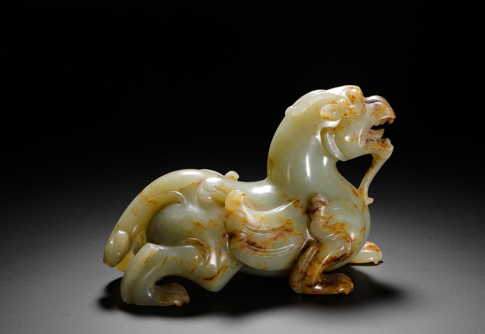 HAN DYNASTY HETIAN JADE TIANLU: H:8cm (3.15in) W:13cm (5.12in) Weight:580g (1.28lb)This is a Han Dynasty carving of the mythical beast Tianlu in celadon jade, with natural russet inclusions. The powerful, dynamic form and sharp, flu