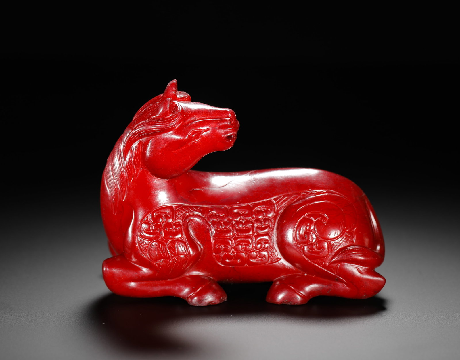 RED JADE RECLINING HORSE FROM THE WARRING STATES PERIOD: H:11cm (4.33in) W:8cm (3.15in) Weight:520g (1.15lb)A recumbent horse ornament carved from red material. Fully scarlet in color, it is a round sculpture of a reclining horse turning its head. The horse