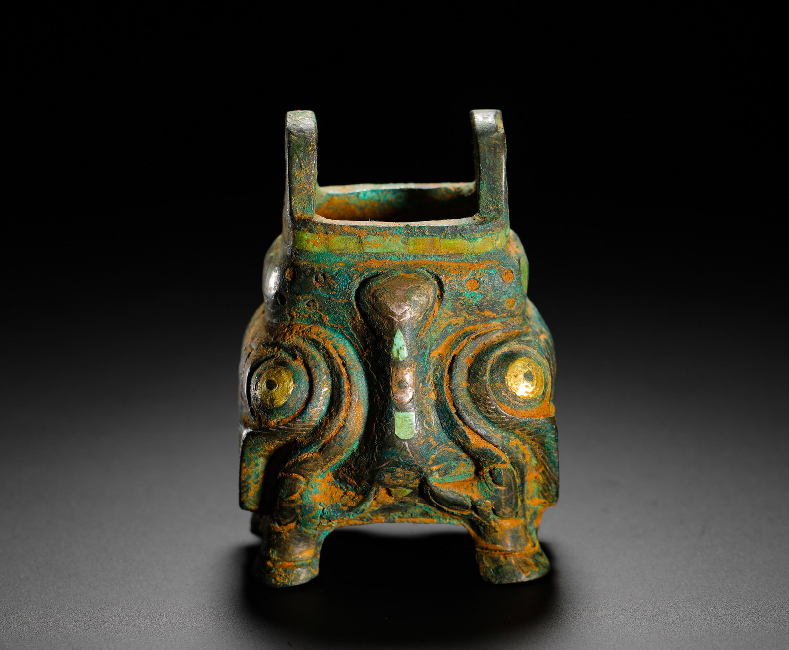 SHANG DYNASTY BRONZE WITH INLAID GOLD AND SILVER INLAID TURQUOISE OWL-SHAPED TRIPOD: H:7.5cm (2.95in) W:5cm (1.97in) Weight:240g (0.53lb) This ding is a late Shang Dynasty bronze vessel shaped like an owl. The surface is decorated with intricate patterns inlaid with gold, silver, and 