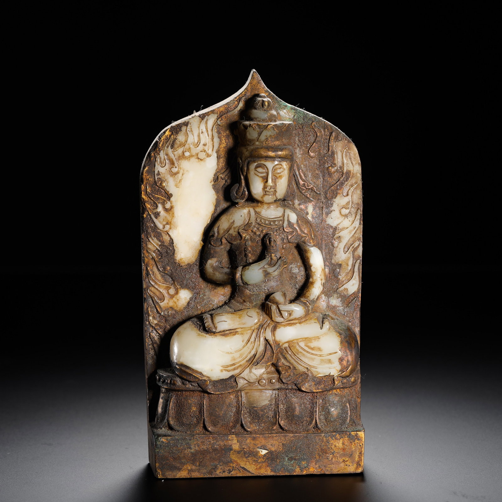 A HETIAN JADE STATUE OF GUANYIN BODHISATTVA FROM THE NORTHERN WEI DYNASTY: H:17.5cmW:9.3cmWeight:890g Gilded bronze backplate base inlaid with white jade Guanyin, seated cross-legged holding ritual tools, flame carved aureole, bronze covered in ancient patina, a medieval Bud