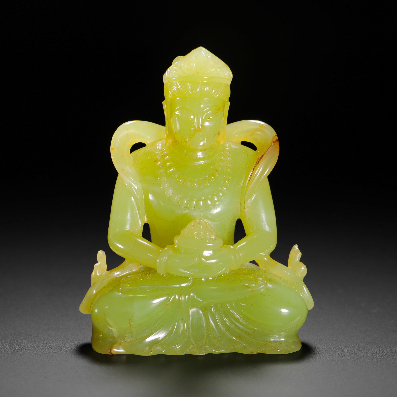 A SEATED STATUE OF THE YELLOW JADE GUANYIN FROM THE QING DYNASTY: H:7.5cm (2.95in) W:5.5cm (2.17in) Weight:130g (0.29lb)This is a Qing Dynasty seated Guanyin statue carved from smooth yellow jade with even color and natural reddish-brown inclusions. The Guanyin is d