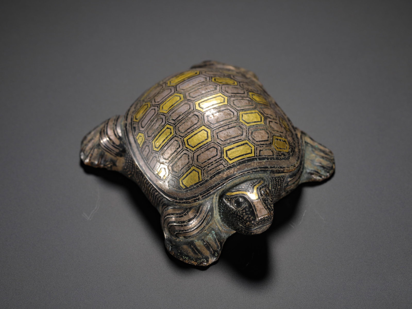 HAN DYNASTY BRONZE INLAID GOLD AND SILVER TURTLE-SHAPED MAT: H:3cm(1.18in)W:8.5cm(3.35in)Weight:240g(0.53lb)These objects were used to hold down mats. The turtle motif symbolized longevity and good fortune, while the use of gold and silver inlay signified the o