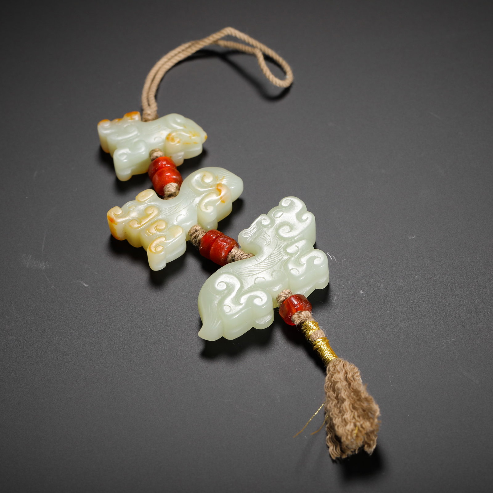 QING DYNASTY IMITATION ANCIENT HETIAN JADE AUSPICIOUS BEAST PENDANT: H:4.5cm (1.77in) W:3.5cm (1.38in) Weight:50g (0.11lb)This is a Qing Dynasty archaistic Hetian jade pendant group, consisting of three greenish-white jade beast pendants and red agate beads. The jade h