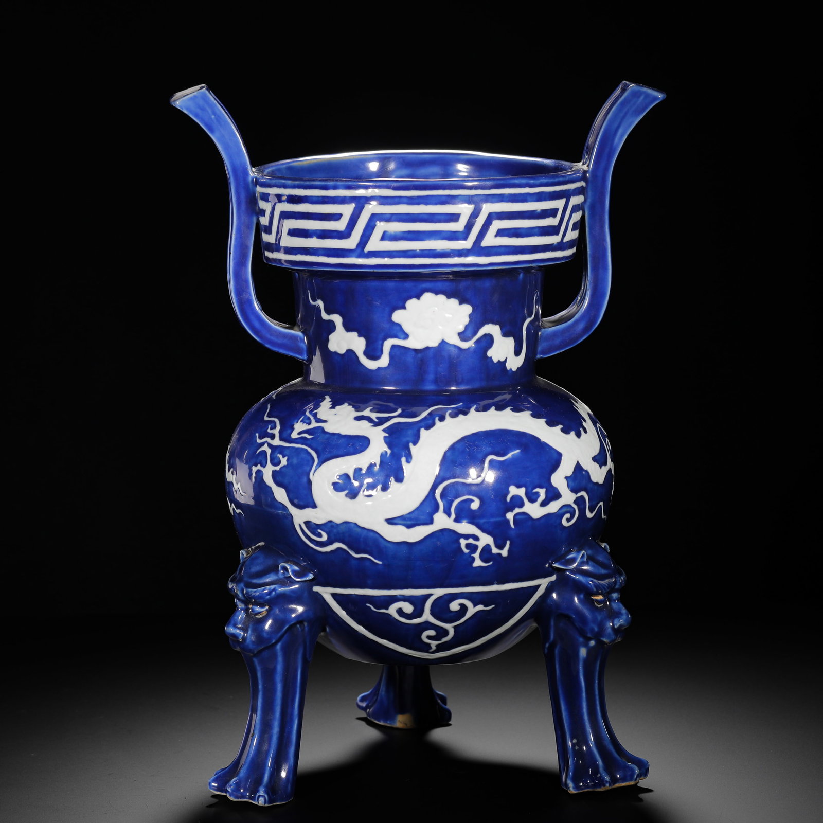 YUAN DYNASTY BLUE GROUND WITH WHITE CLOUD DRAGON PATTERN BEAST STOVE: H:40cmW:29cmWeight:5900g Porcelain censer modelled after bronze ding vessel, covered in sapphire blue glaze with raised white relief. Main body decorated with dragon amid clouds, neck with cloud motif