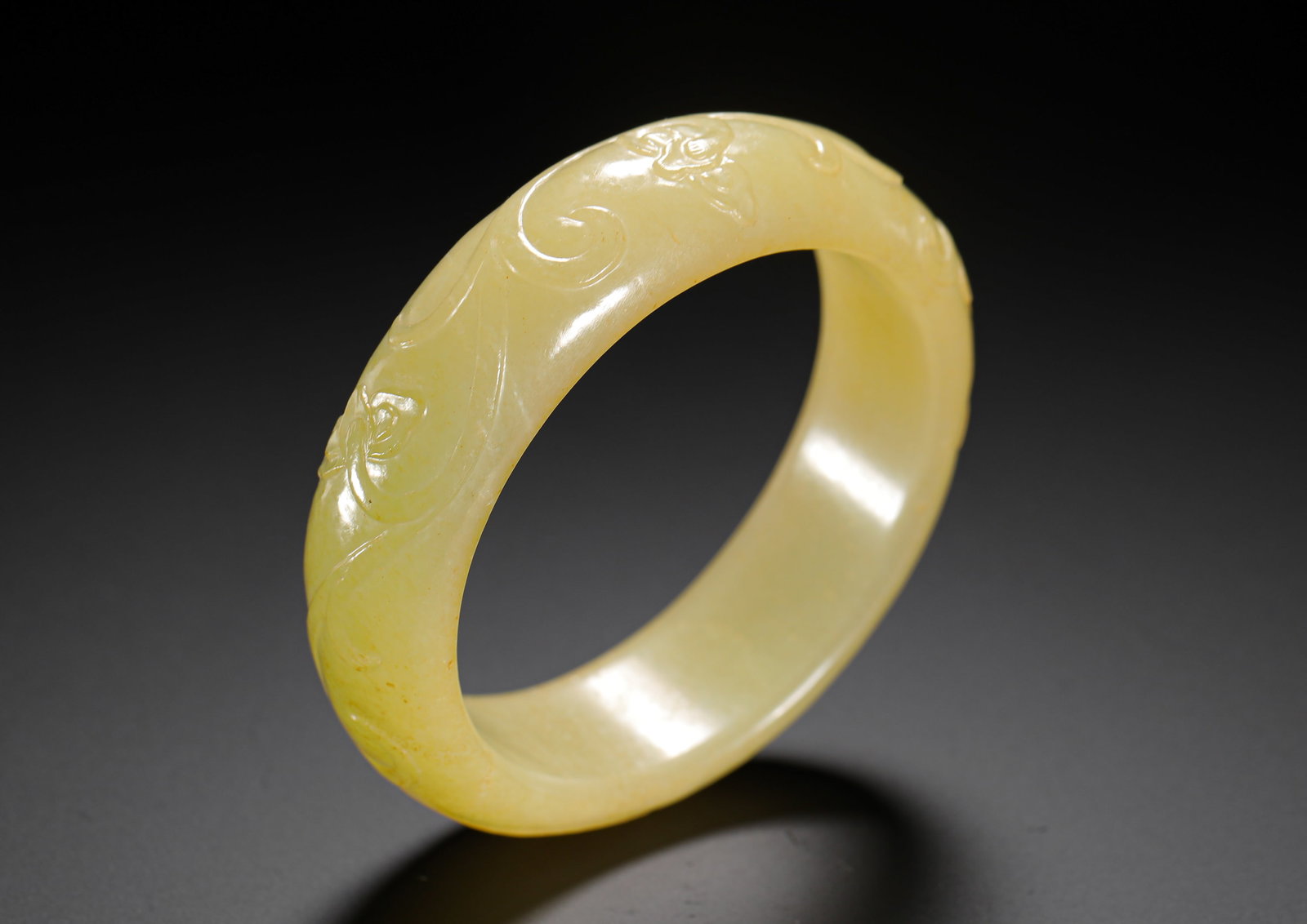 QING DYNASTY HETIAN YELLOW JADE FLOWER-PATTERNED WIDE-RIMMED BRACELET: Outer diameter:7.5 cm (2.95in) Inner diameter: 5.7cm (2.24in) Weight:70g (0.15lb)This is a Qing Dynasty Hetian yellow jade bangle with a smooth texture and even warm yellow hue. Featuring a wide band 