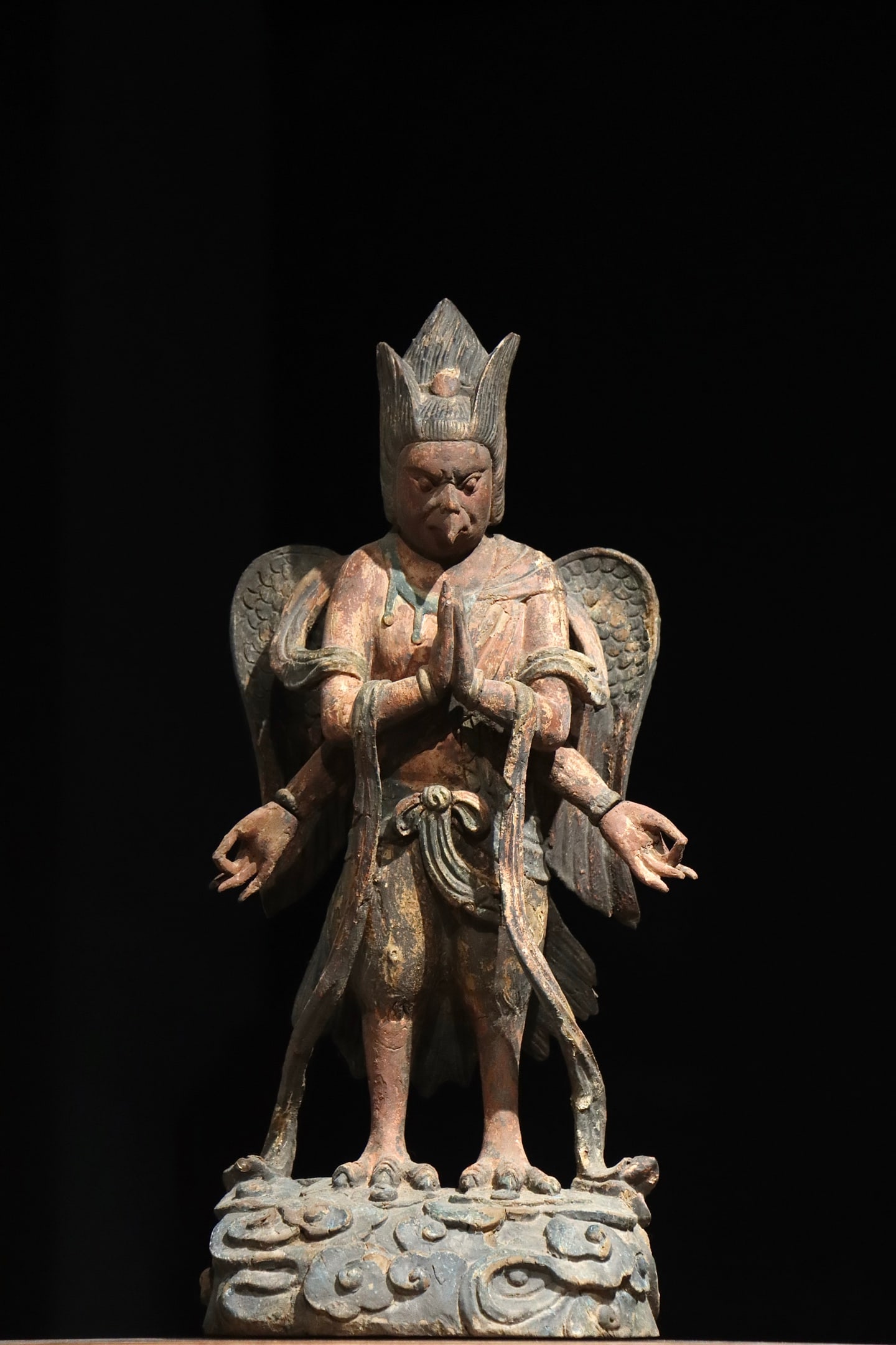 TANG DYNASTY WOODCARVING PAINTED MULTI-ARMED GARUDA: H:53cm?20.87in?Carved wood with original painted pigments. The figure has an eagle beak, human face and a pair of wings on its back, with four arms in varied gestures, standing on a cloud-patterned ba