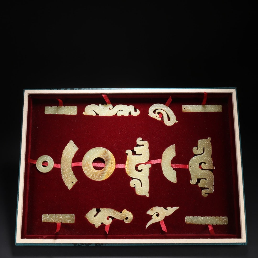 A set of fourteen jade pendants from the Han Dynasty, made of Hetian jade: Long:9.8cm(3.86in), Width:4.4cm(1.73in), Thick:0.4cm(0.16in), Weight:31g (0.068lb), Weight:235g (0.518lb)Housed in a brocade box, this assemblage consists of various ancient jade components including 