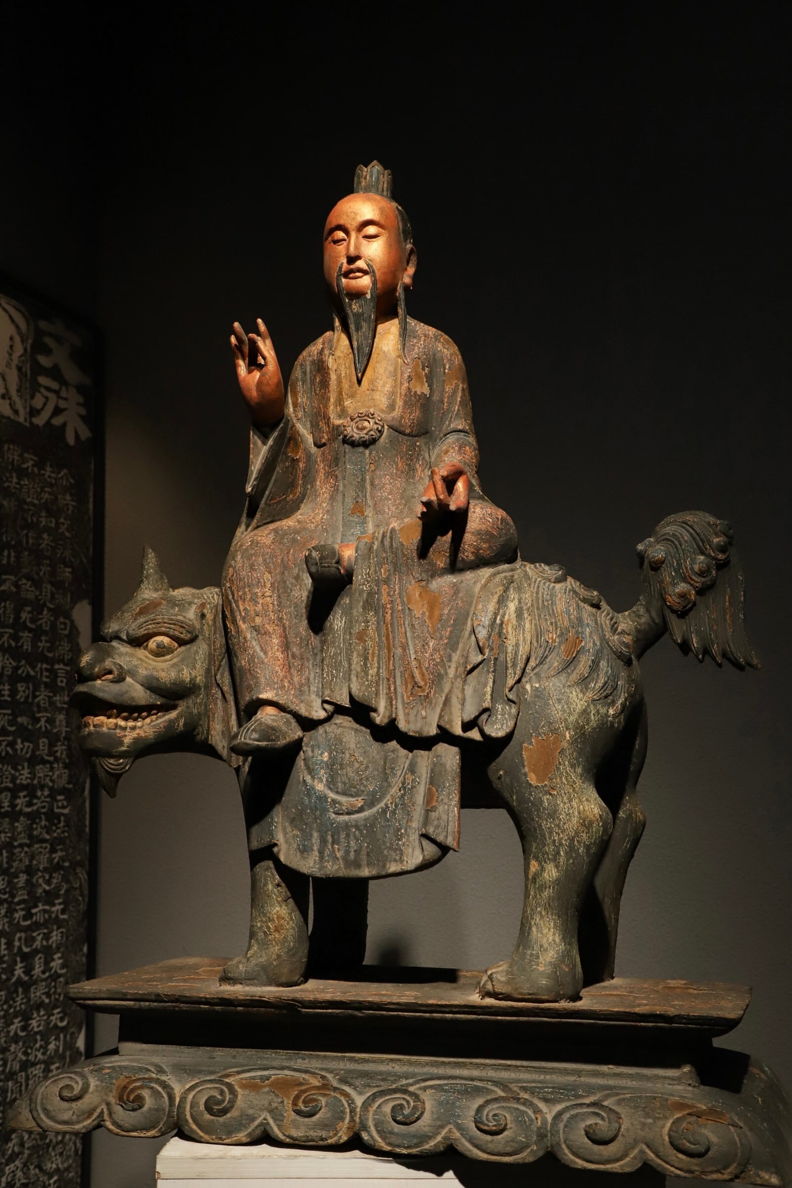 A PAINTED WOODCARVING OF THE MING DYNASTY DEPICTING THE GREAT LORD OF SALVATION RIDING A LION