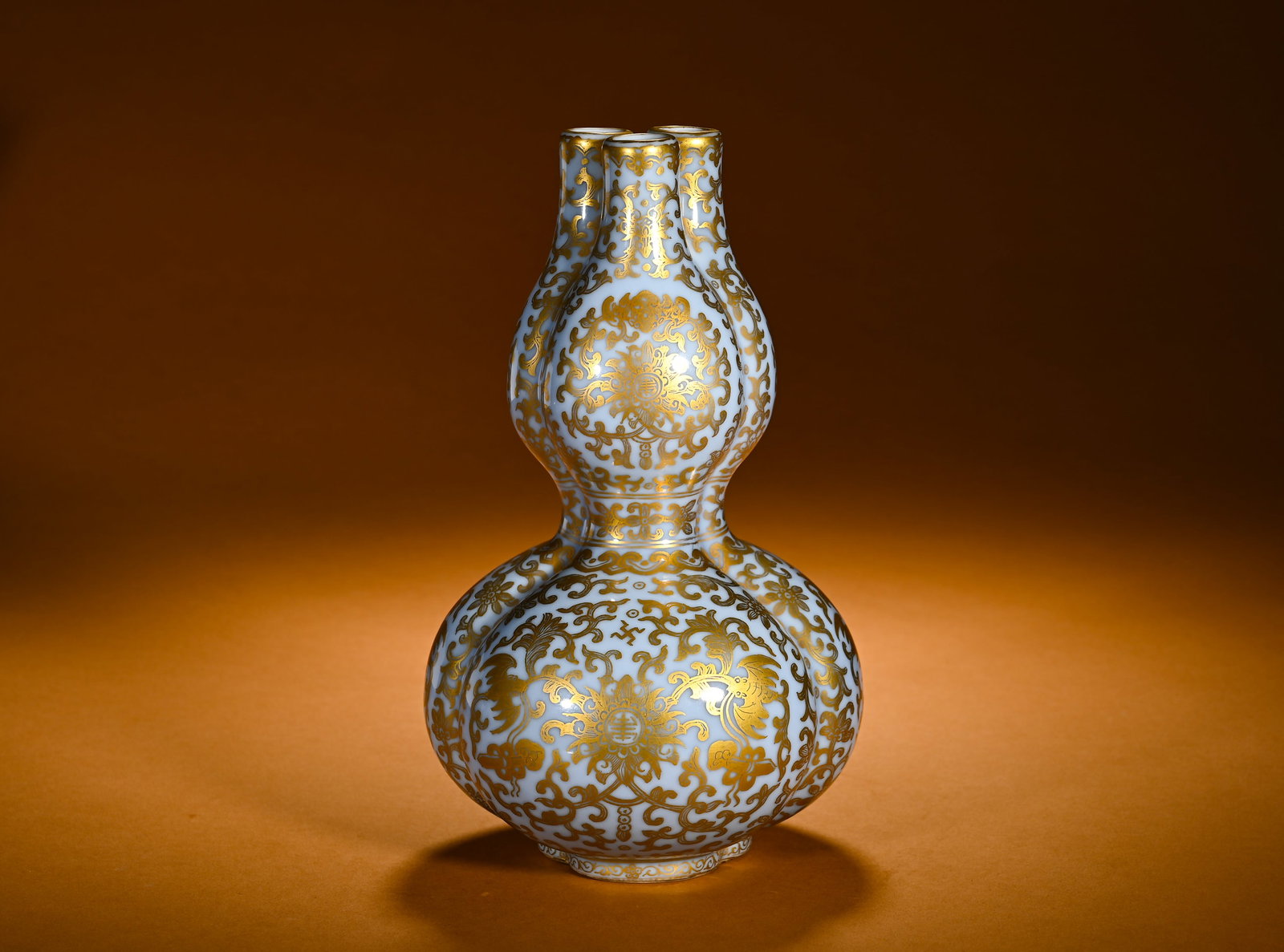 QING DYNASTY SKY BLUE GLAZED GILDED LOTUS AND LONGEVITY PATTERN TRIPLET GOURD VASE: Height:21cm(8.27in)Width:13cm(5.12in)Weight:1020g(2.25lb)Sky-blue glazed tripartite gourd vase with gilded lotus scroll, bat and longevity motif. Innovative Qianlong shape with three conjoint gourd bo
