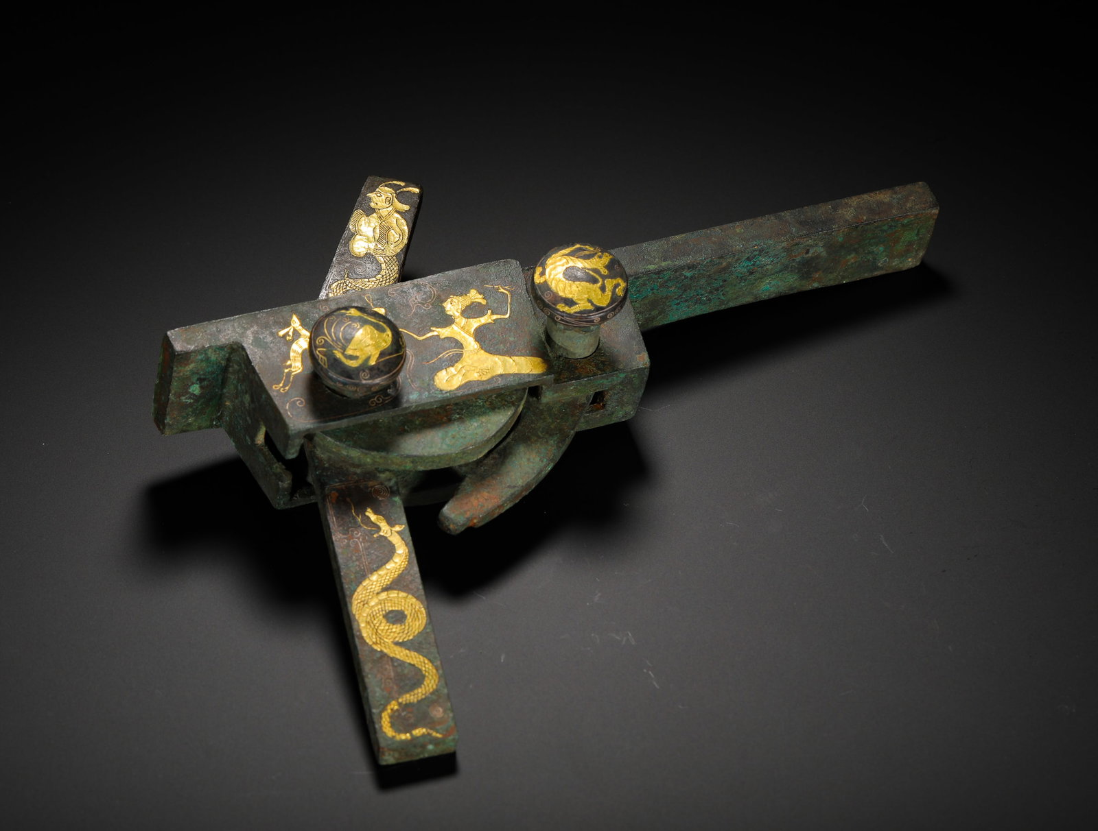BRONZE CROSSBOWS WITH GILDED DIVINE FIGURES AND DRAGON PATTERNS FROM THE HAN DYNASTY: Height:18cm(7.09in) Width:21cm(8.27in) Weight:1040g(2.29lb)Han Dynasty bronze crossbow trigger mechanism decorated with gold-inlaid immortal and dragon motifs. All surfaces are finely engraved with au