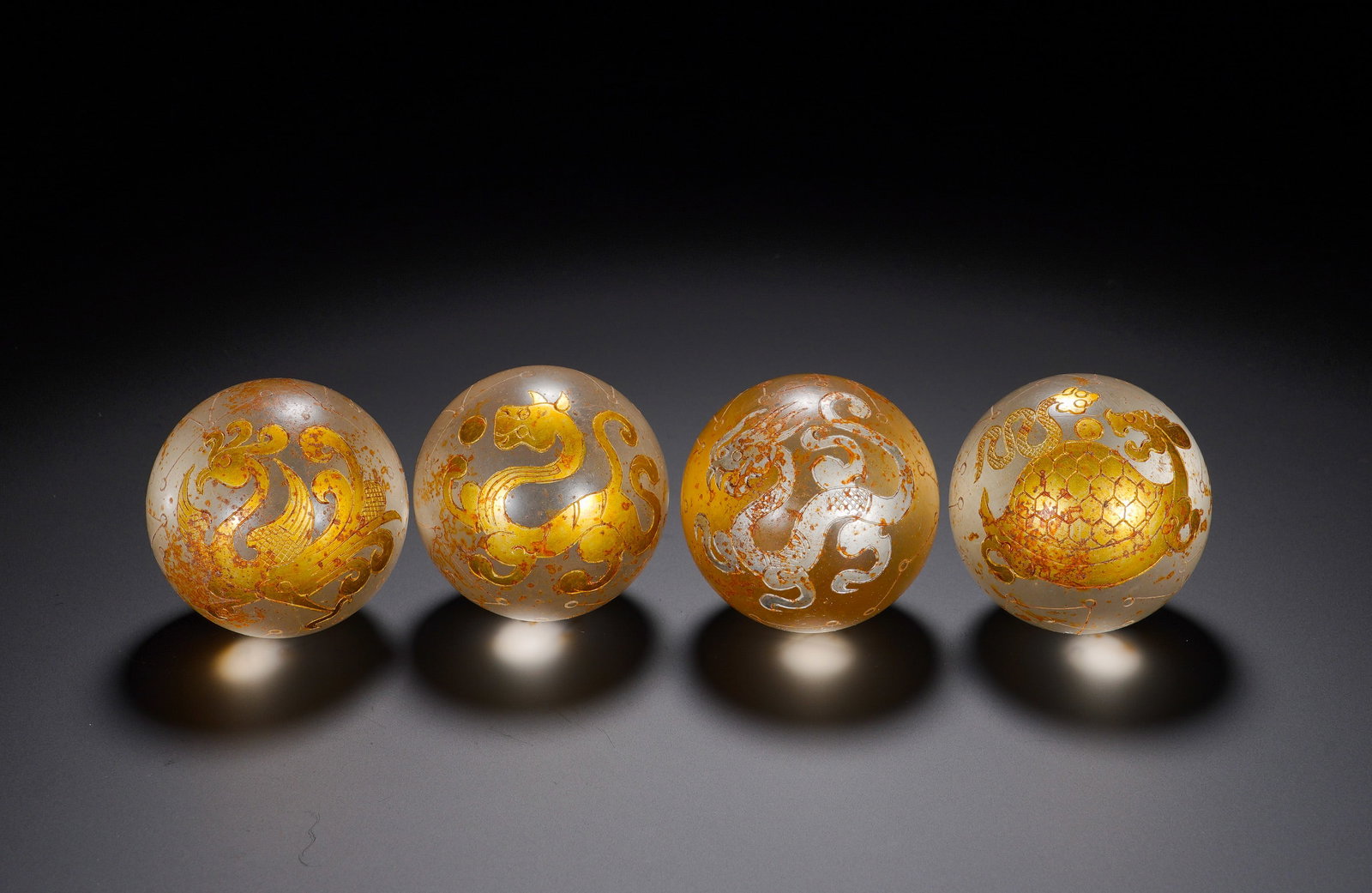 A SET OF FOUR HAN DYNASTY CRYSTAL INLAID GOLD AND SILVER FOUR SPIRITS PATTERN BEADS
