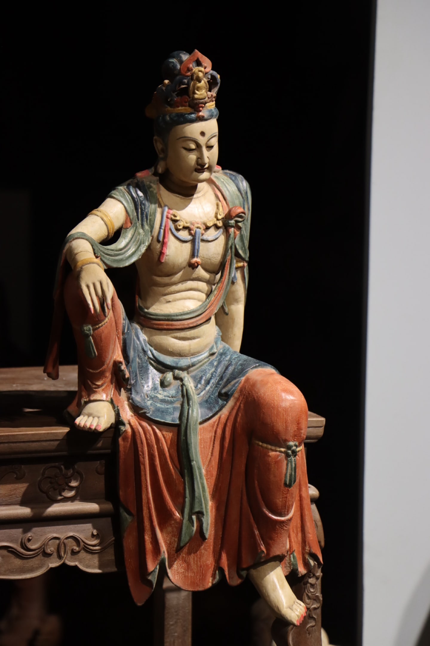 LIAO DYNASTY WOODCARVING OF GUANYIN: Height:62cm (24.41in)Wooden polychrome Guanyin Bodhisattva in relaxed sitting posture, small Buddha carved on crown, layered pearl necklaces, draped robes painted with traditional mineral colors, Chin