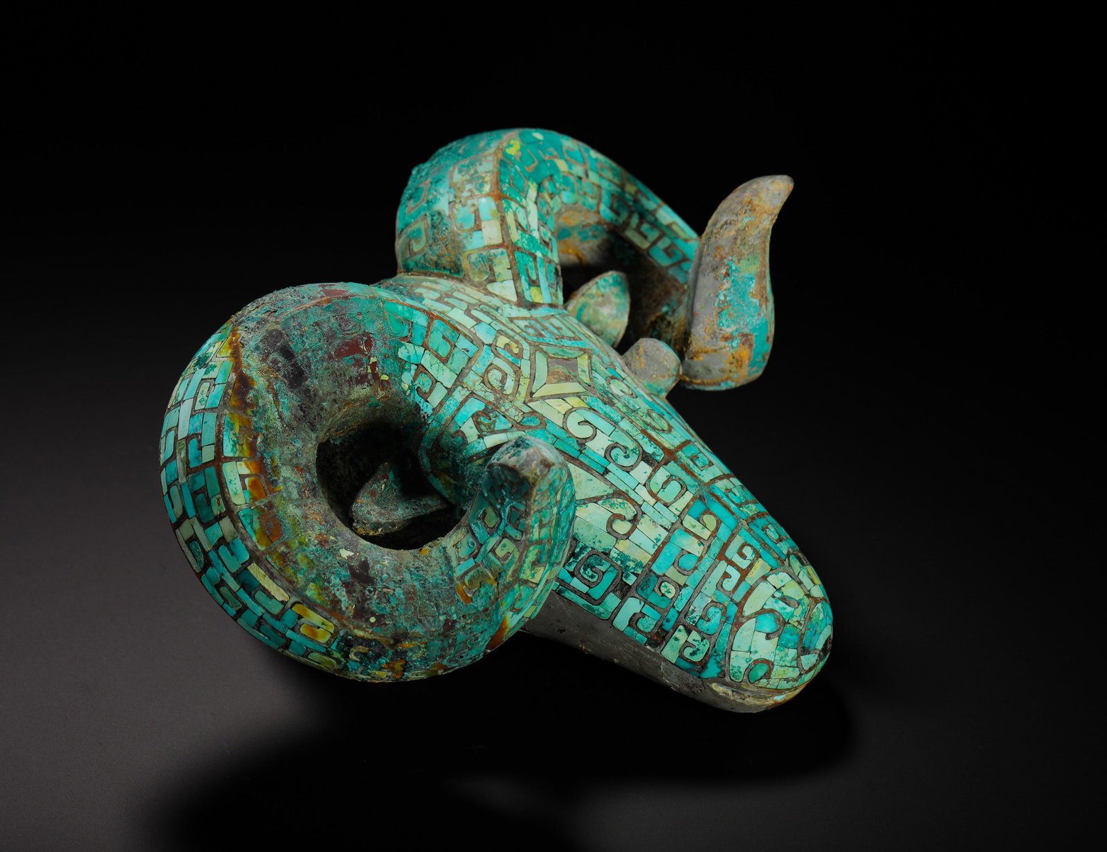 BRONZE SHEEP HEAD INLAID WITH TURQUOISE FROM THE WESTERN ZHOU DYNASTY: Height:12cm(4.72in) Width:20cm(7.87in) Weight:1340g(2.95lb)Shang / Western Zhou bronze sheep-head chariot ornament. Its entire surface is densely inlaid with tiny turquoise slices arranged into square