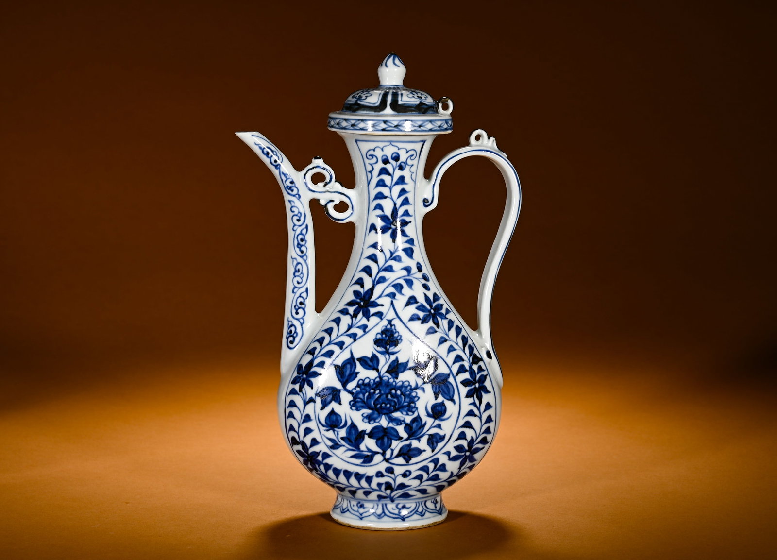 MING DYNASTY BLUE AND WHITE RHOMBUS-SHAPED AND POLISHED PEONY PATTERN EWER: Height:27cm(10.63in)Width:16cm(6.30in)Weight:710g(1.57lb)Blue and white ewer with peony in rhombus panel. Elegant pear-shaped body with slender neck, curved spout and scroll cloud handle, lid topped b