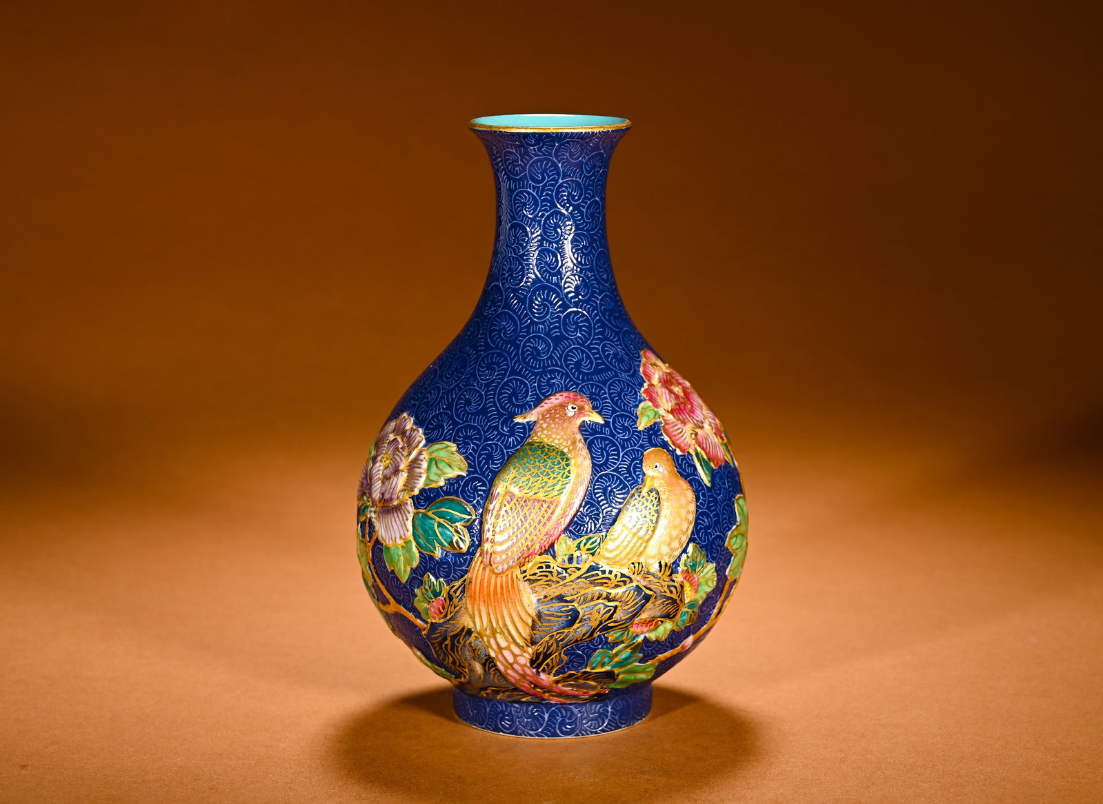 A QING DYNASTY BLUE GROUND, EMBOSSED AND GILDED GOLDEN PHEASANT AND PEONY PATTERN JADE VASE: Height:17cm(6.69in)Width:12cm(4.72in)Weight:600g(1.32lb)Famille rose pear-shaped vase with embossed golden pheasant and peony on blue incised ground. Elegant pear-shaped vessel with flared rim, curved