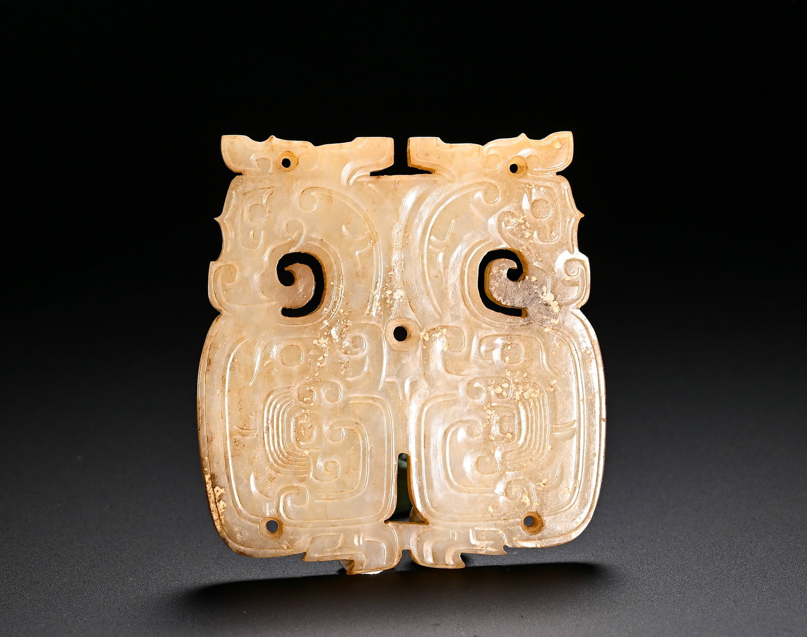 SPRING AND AUTUMN HETIAN JADE DOUBLE DRAGON PATTERN JADE PENDANT: Height:6.7cm(2.64in)Width:6cm(2.36in)Weight:50g(0.11lb)Spring and Autumn Period Hetian jade plaque carved with twin dragons. Adopting symmetrical composition, the plaque is decorated with confronting 