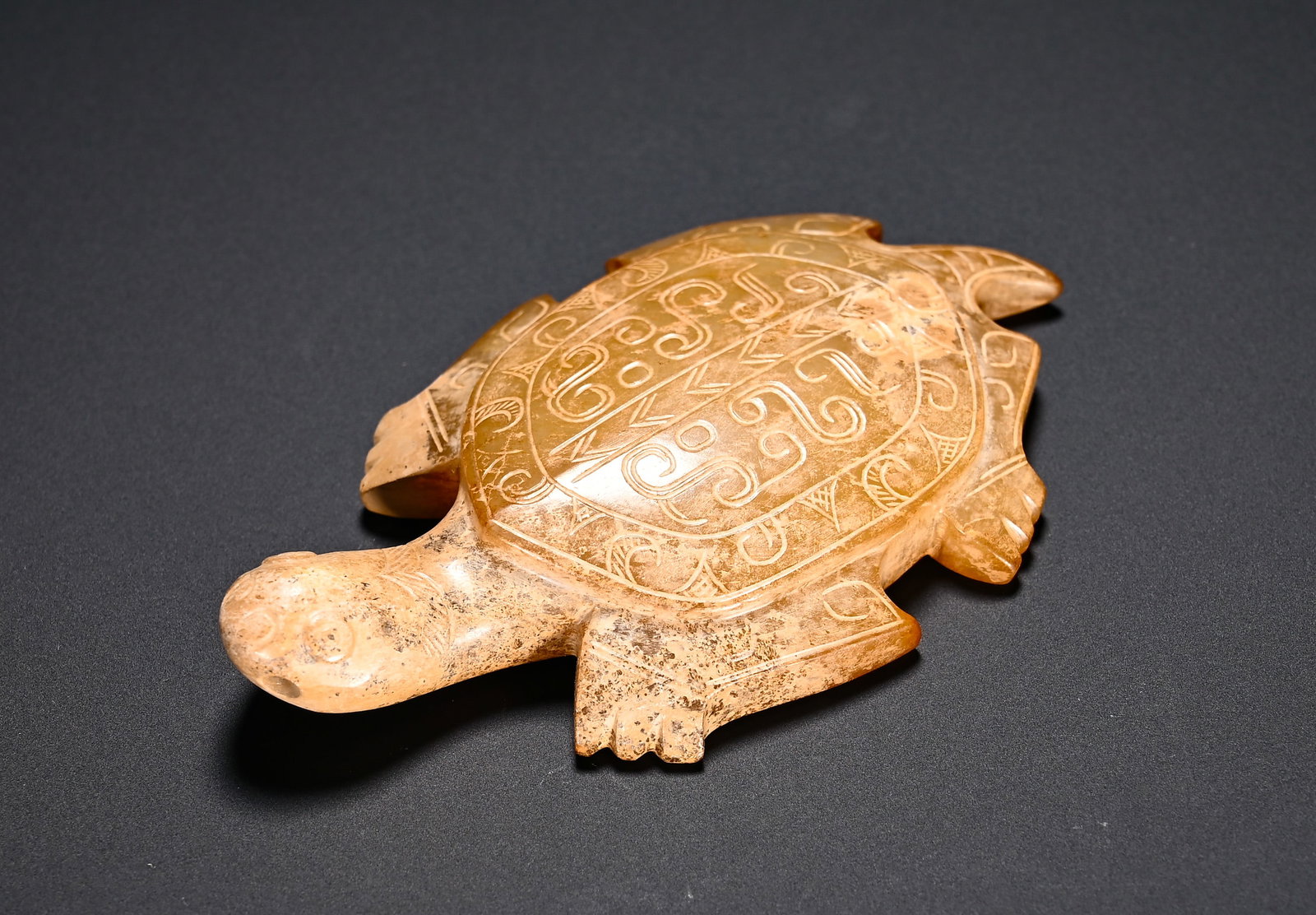SHANG AND ZHOU HETIAN JADE TURTLE PENDANT: Height:1.5cm(0.59in)Width:7.8cm(3.07in)Weight:50g(0.11lb)Shang-Zhou Dynasty Hetian jade turtle pendant. The turtle is carved in a prone posture with plump carapace incised with scroll cloud and triang