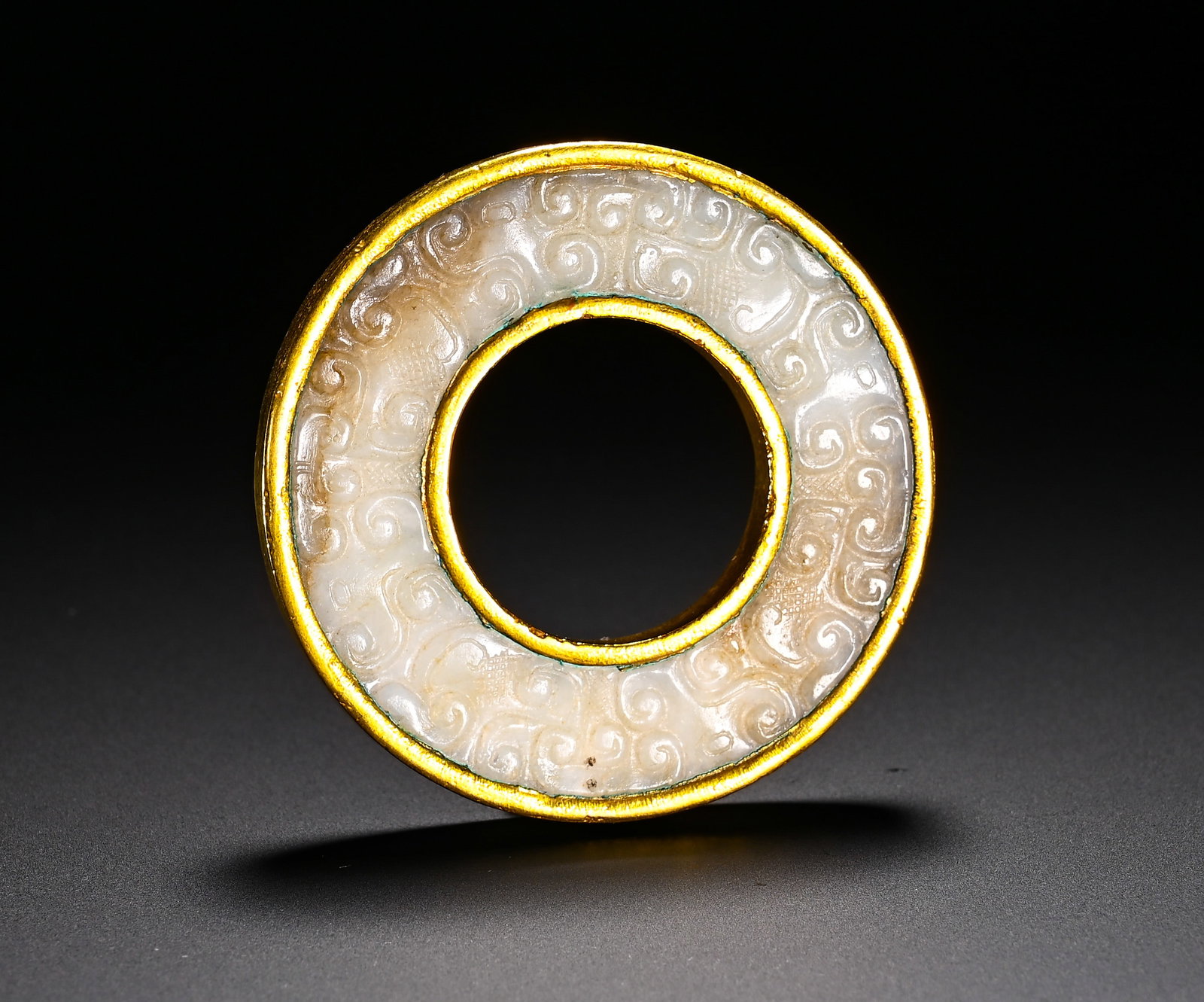 SPRING AND AUTUMN HETIAN JADE GOLD-ENCRUSTED CLOUD PATTERN JADE RING: Diameter:6.1cm(2.40in)Weight:50g(0.11lb)Spring and Autumn Period Hetian jade ring wrapped with gold, decorated with scroll cloud patterns. Both sides of the ring are incised with scroll cloud motifs o