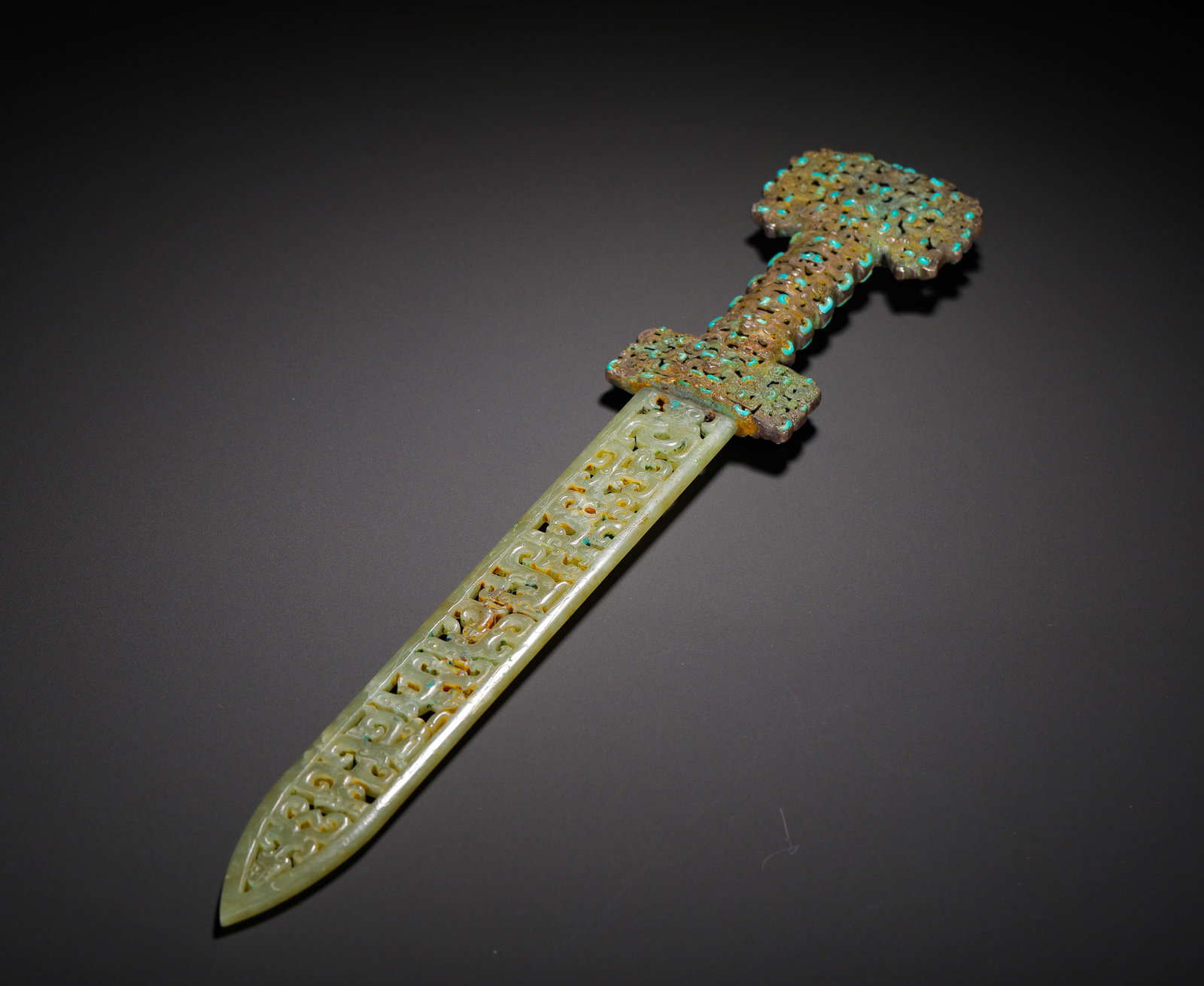 BRONZE HANDLE HOLLOWED-OUT CHILONG AND TIAN JADE SWORD FROM THE WARRING STATES PERIOD: Long:39cm(15.35in) Width:6.5cm(2.56in) Weight:330g(0.73lb)Antique hollowed jade sword carved with intertwined chi dragons, bronze hilt fully inlaid with turquoise, phoenix patterns piercing the blade,