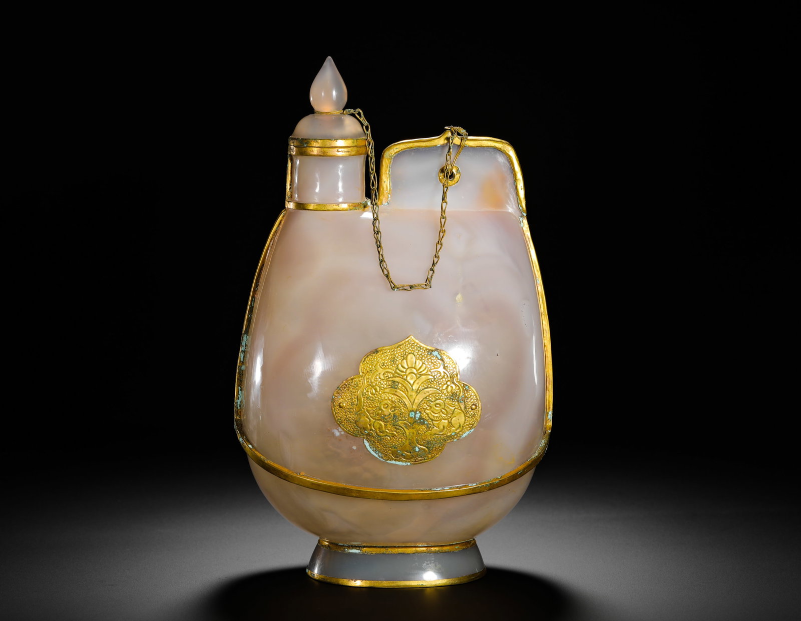 QING DYNASTY WHITE AGATE GOLD-ENCASED LEATHER VESSEL: Height:26cm(10.24in) Width:16cm(6.30in) Weight:870g(1.92lb)Qing Dynasty pale white agate leather-skin shaped wine flask with full gilt fittings. Solid hollowed agate carving imitating nomadic leather