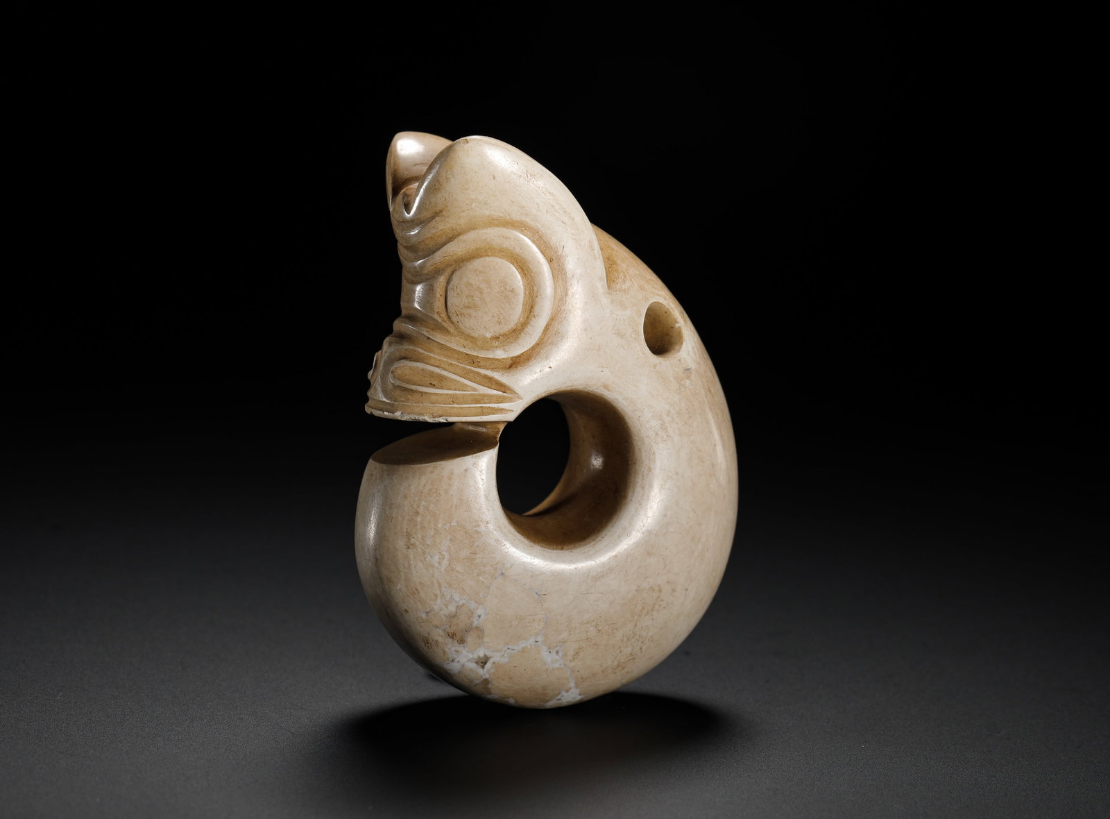 RED MOUNTAIN PERIOD JADE PIG-DRAGON: Height:8cm(3.15in) Width:5.8cm(2.28in) Weight:160g(0.35lb)Hongshan culture jade pig-dragon pendant fully calcified into bone-white texture. Integrated solid C-form carving with perforated side for thr