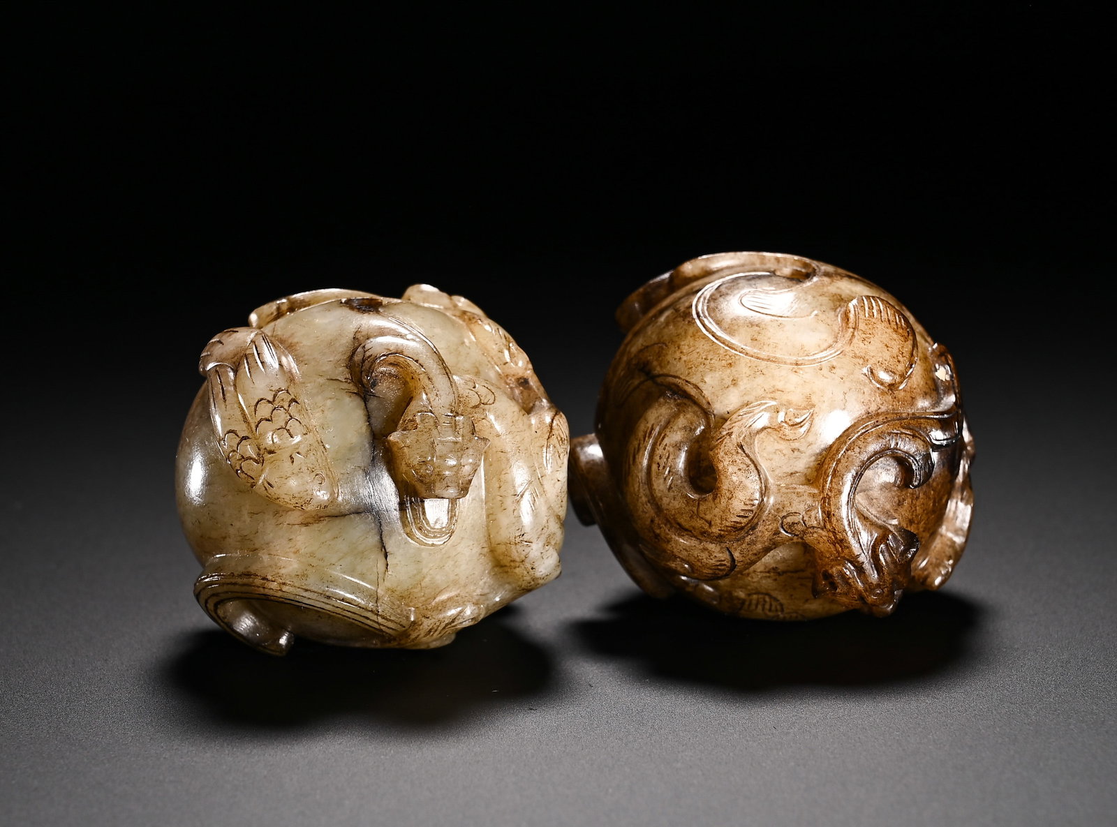 A PAIR OF HAN DYNASTY HETIAN JADE DRAGON AND PHOENIX PATTERNED JADE BEADS: Diameter:4cm(1.57in)Weight:260g(0.57lb)Han Dynasty Hetian jade paired spherical pendants carved with chi dragons and phoenixes. Each plump spherical bead is decorated with high-relief intertwined chi 