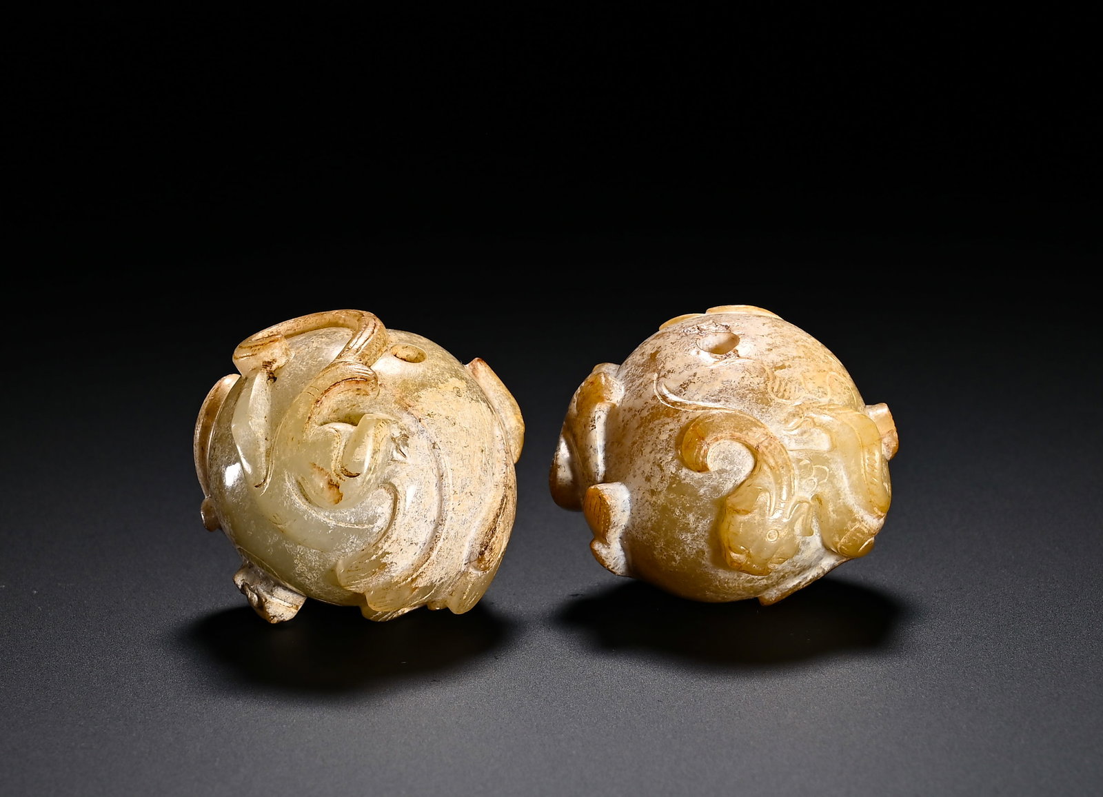 A PAIR OF HAN DYNASTY HETIAN JADE DRAGON AND DRAGON PATTERNED JADE BEADS: Diameter:3.5cm(1.38in)Weight:150g(0.33lb)Han Dynasty Hetian jade paired spherical pendants carved with chi dragons. Each plump round bead is decorated with winding chi dragons in high relief. Holes ar