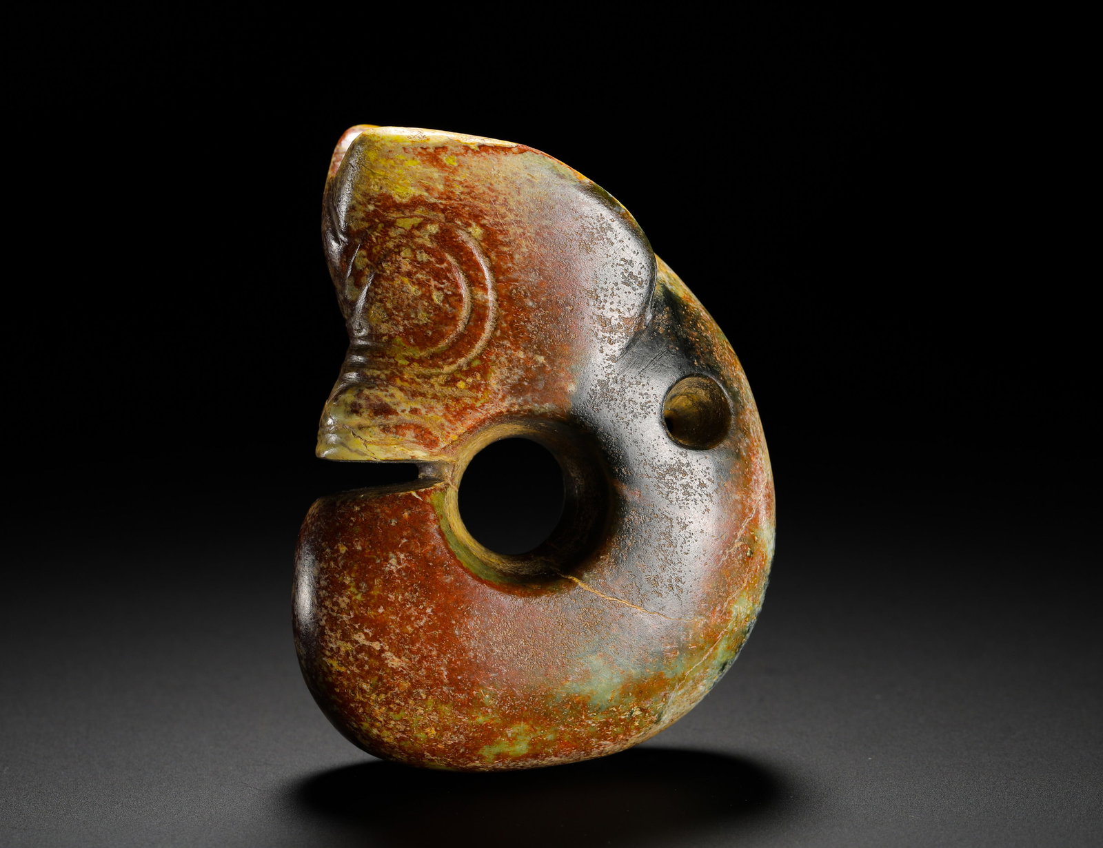 RED MOUNTAIN PERIOD JADE PIG-DRAGON: Height:8cm(3.15in) Width:6cm(2.36in) Weight:270g(0.60lb)Neolithic Hongshan jade pig-dragon pendant carved in C-shape. Integrated solid jade carving with mixed yellow and grey-black burial patina perme