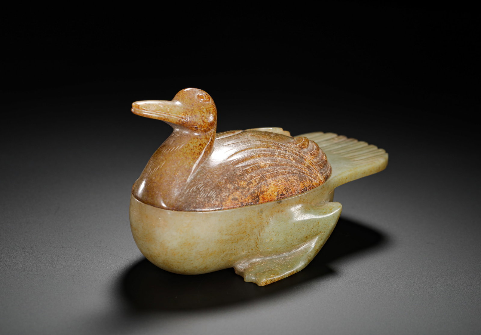TANG DYNASTY HETIAN JADE RED-SOAKED MANDARIN DUCK SHAPED LID BOX: Height:8cm(3.15in) Width:24.5cm(9.65in) Weight:260g(0.57lb)Archaic celadon jade mandarin duck lidded box with russet patina.Separately carved body and lid from one jade mass, fully covered in aged dee